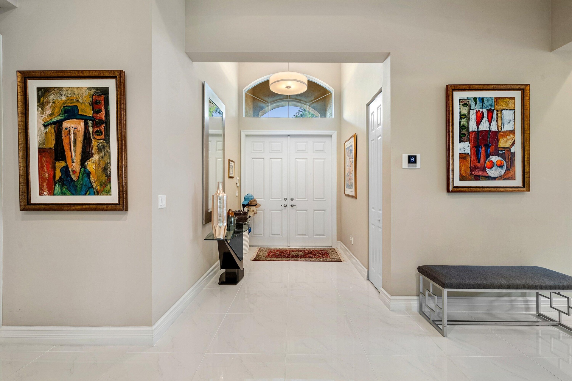 Foyer featuring double-door entry, arched transom window, pendant lighting, and polished stone-finish flooring