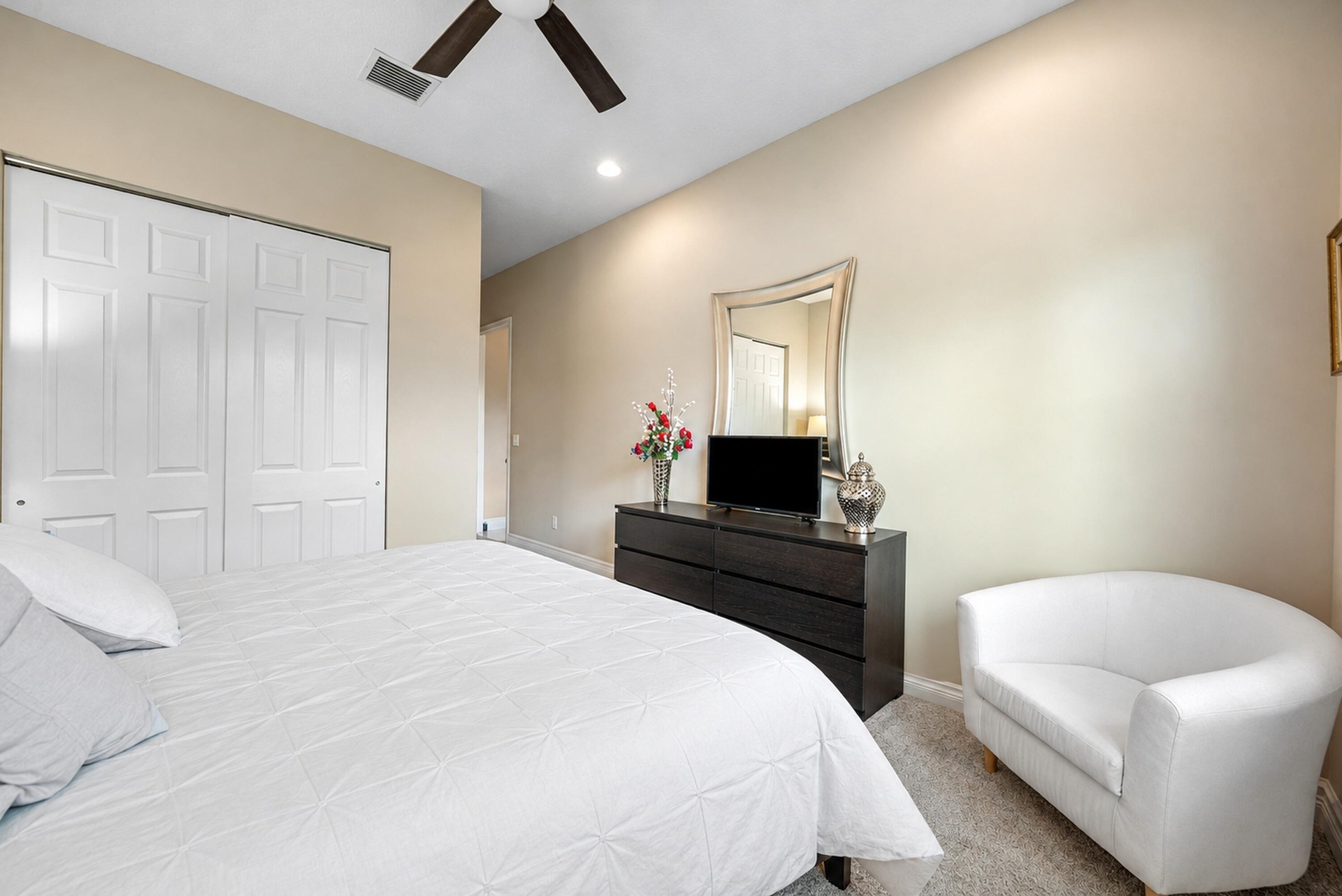Neutral-toned interior featuring carpeting, a ceiling fan, and sliding closet doors