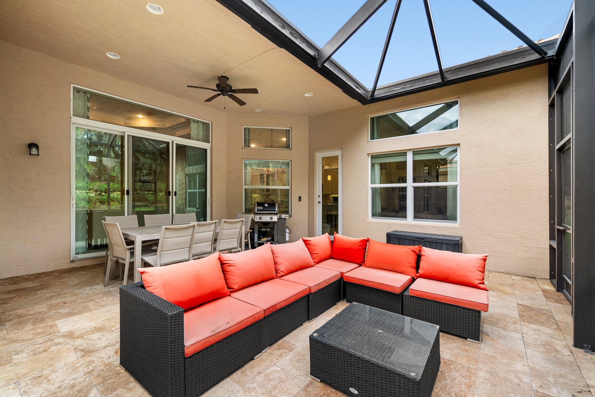 Screened-in patio featuring a vaulted ceiling, stone-finish flooring, ceiling fan, and multi-pane windows