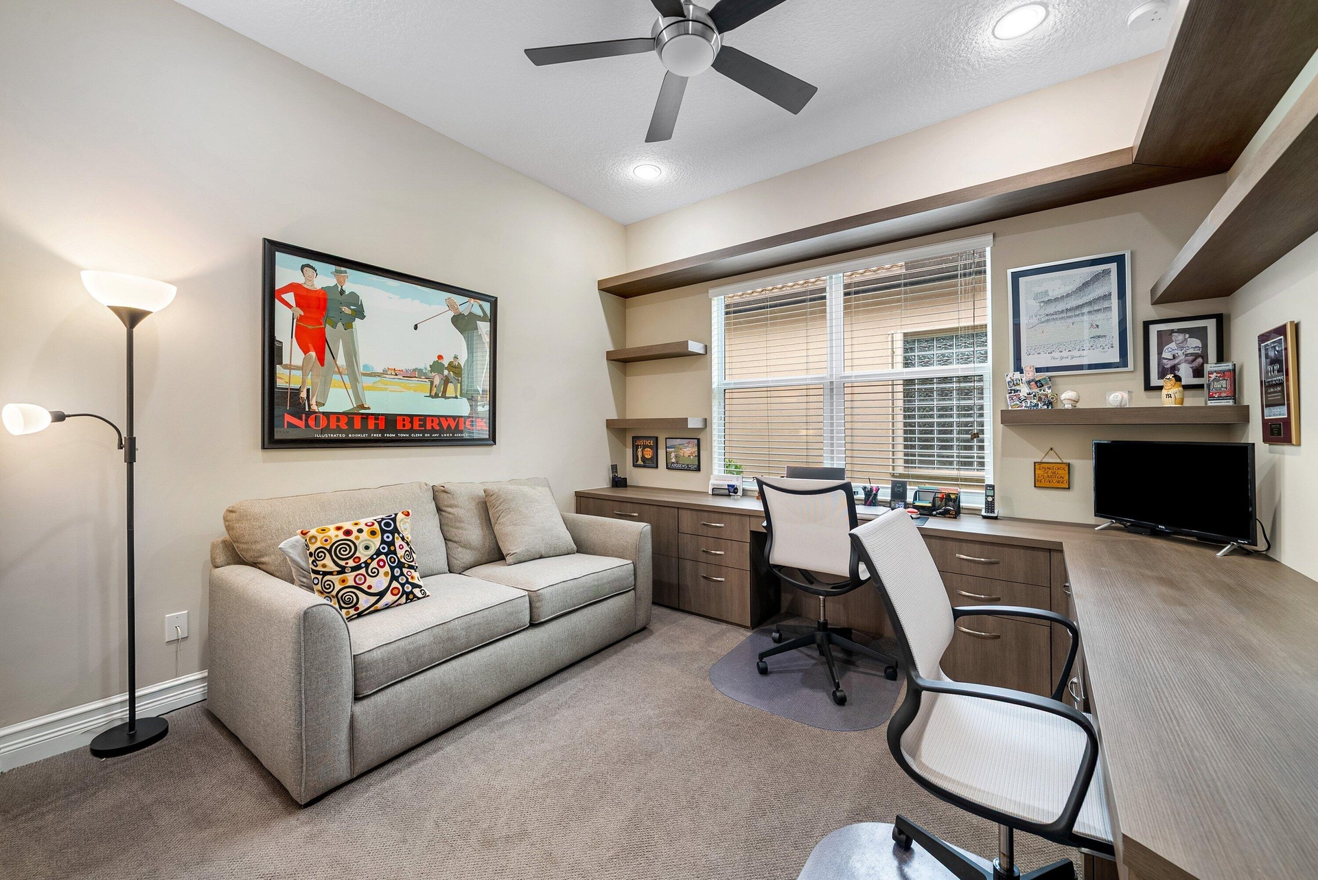 Built-in wood-finish cabinetry, integrated desk workspace, floating shelving, ceiling fan with light fixture, and recessed lighting