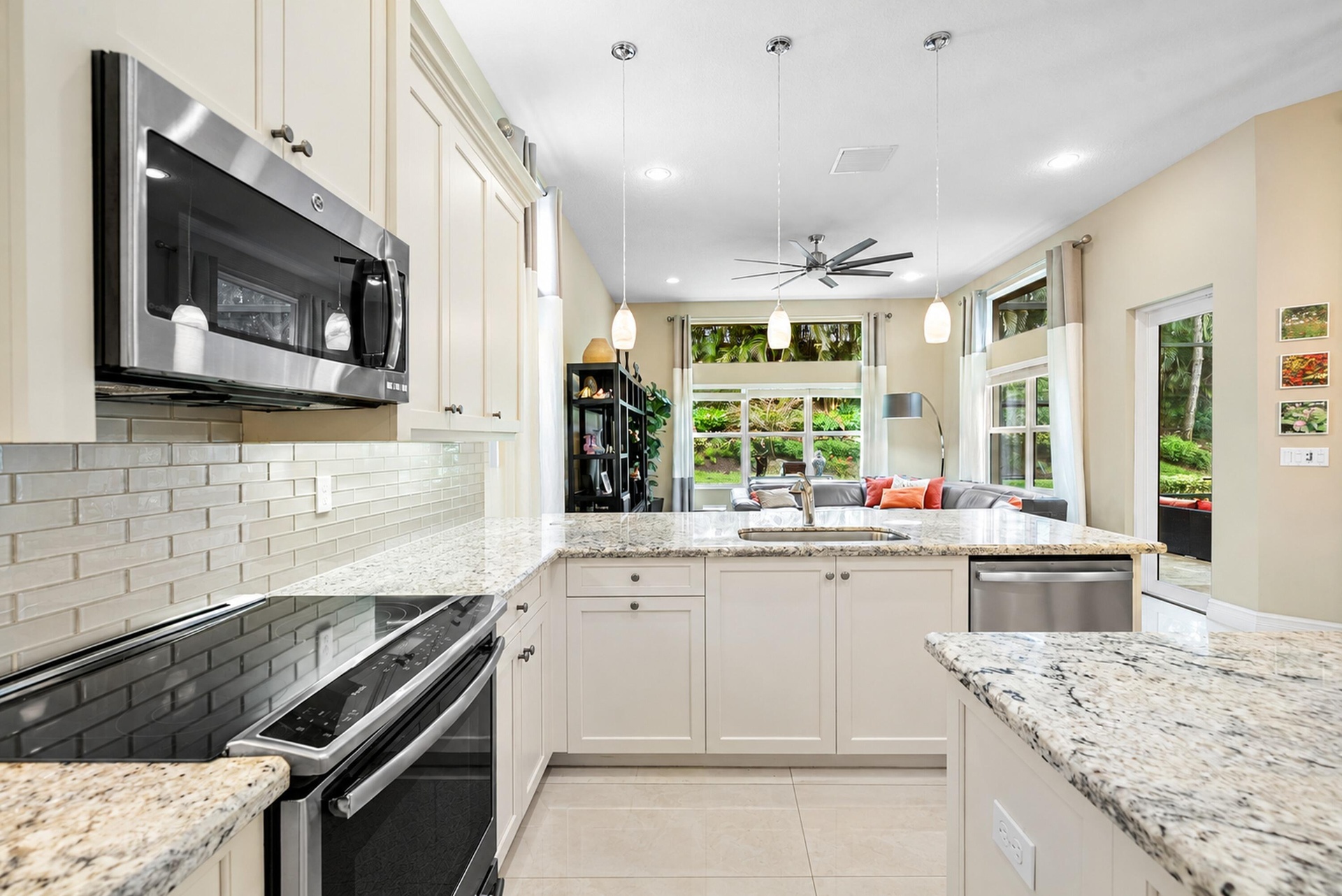 Kitchen featuring shaker-style cabinetry, stone countertops, subway tile backsplash, stainless steel appliances, and three pendant light fixtures