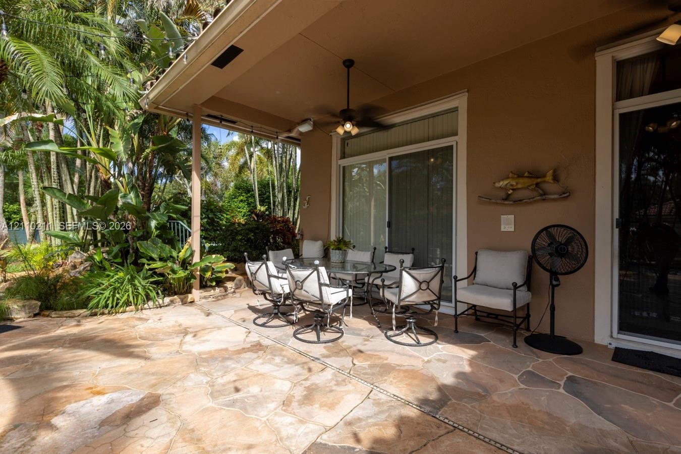Covered patio featuring natural stone flooring, recessed lighting, and a ceiling-mounted fan with integrated light fixture