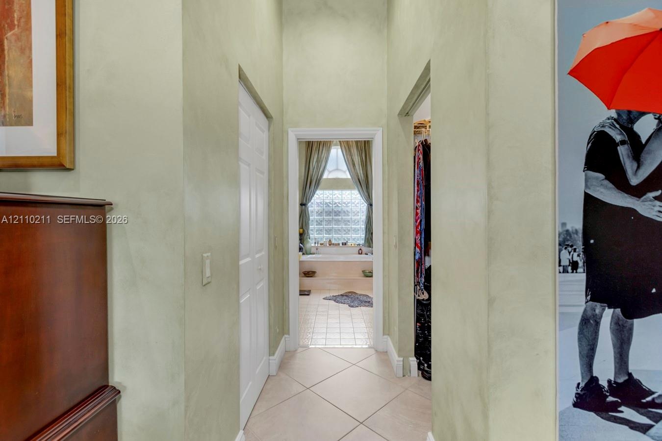 Bathroom featuring a recessed soaking tub with a tiled surround, glass block window, separate shower stall with a glass enclosure, and dual cabinetry 