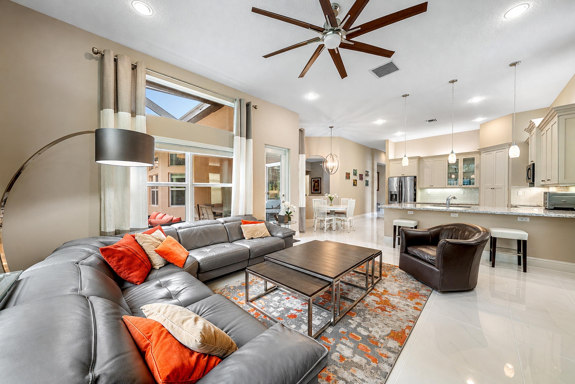 Open-concept living space featuring high ceilings, recessed lighting, expansive picture windows, tile flooring, and kitchen cabinetry with integrated 