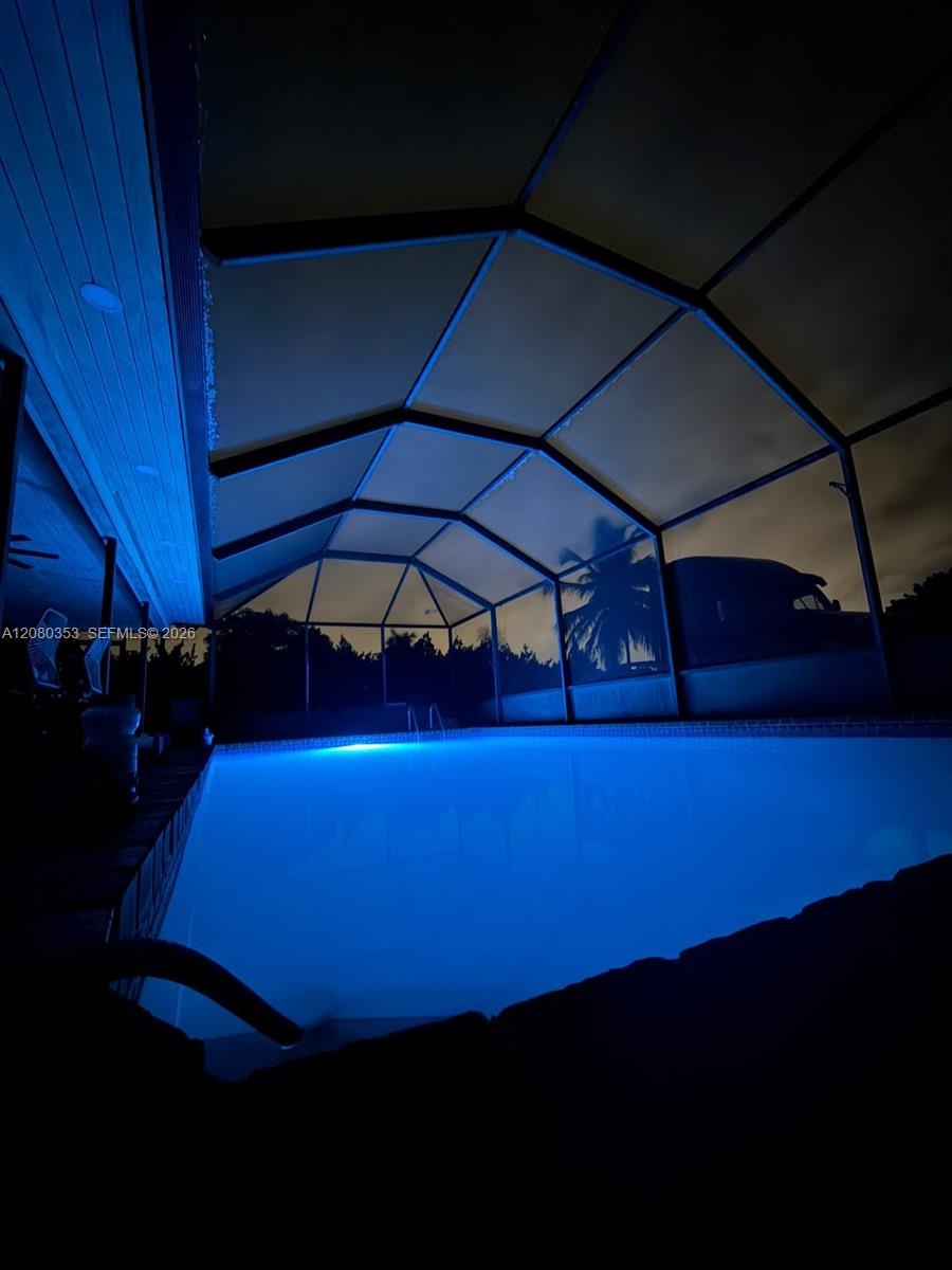 In-ground swimming pool enclosed by a structural screen lanai