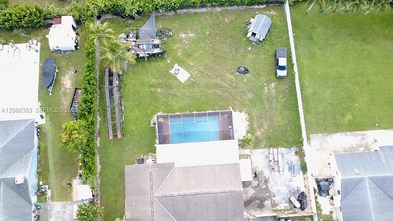 Expansive rear grounds featuring a screened-in swimming pool, a concrete patio area, and mature perimeter landscaping