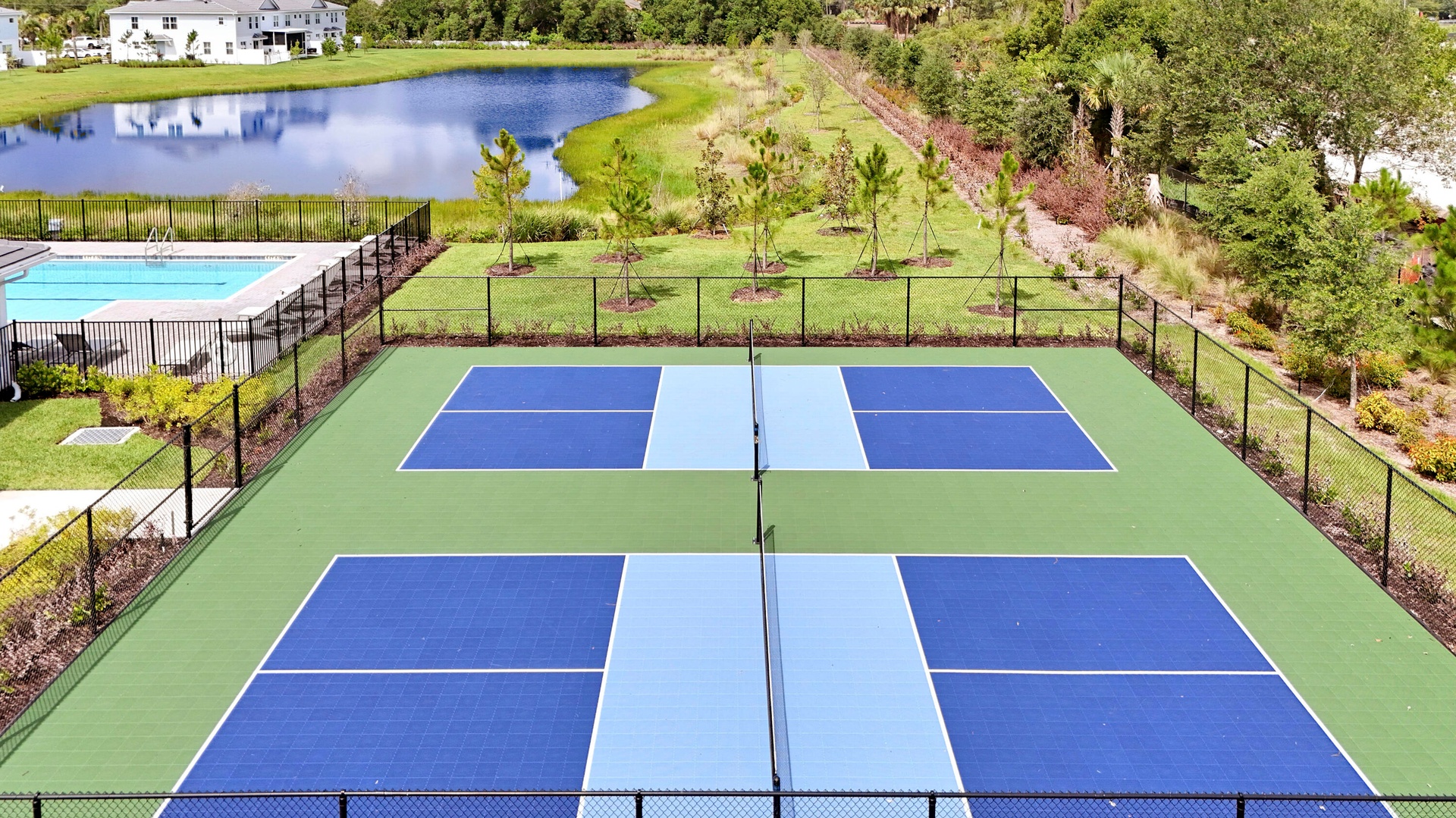 Multi-court athletic facility featuring blue and green surfaces, perimeter chain-link fencing, and an open-air layout.