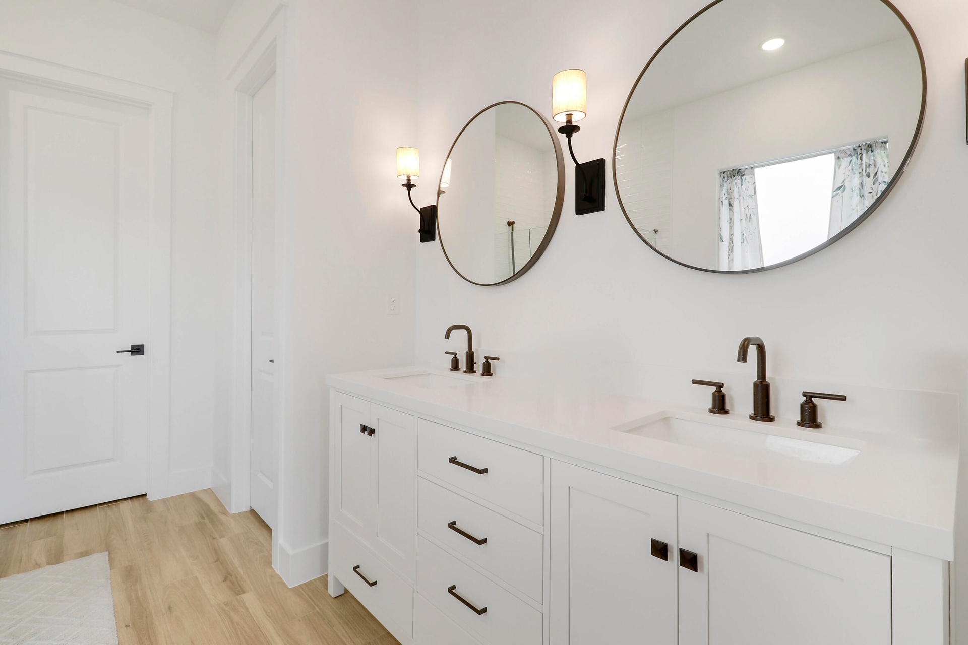 Dual-sink vanity featuring a white composite countertop, undermount sinks, matte black widespread faucets, and shaker-style cabinetry with matte black