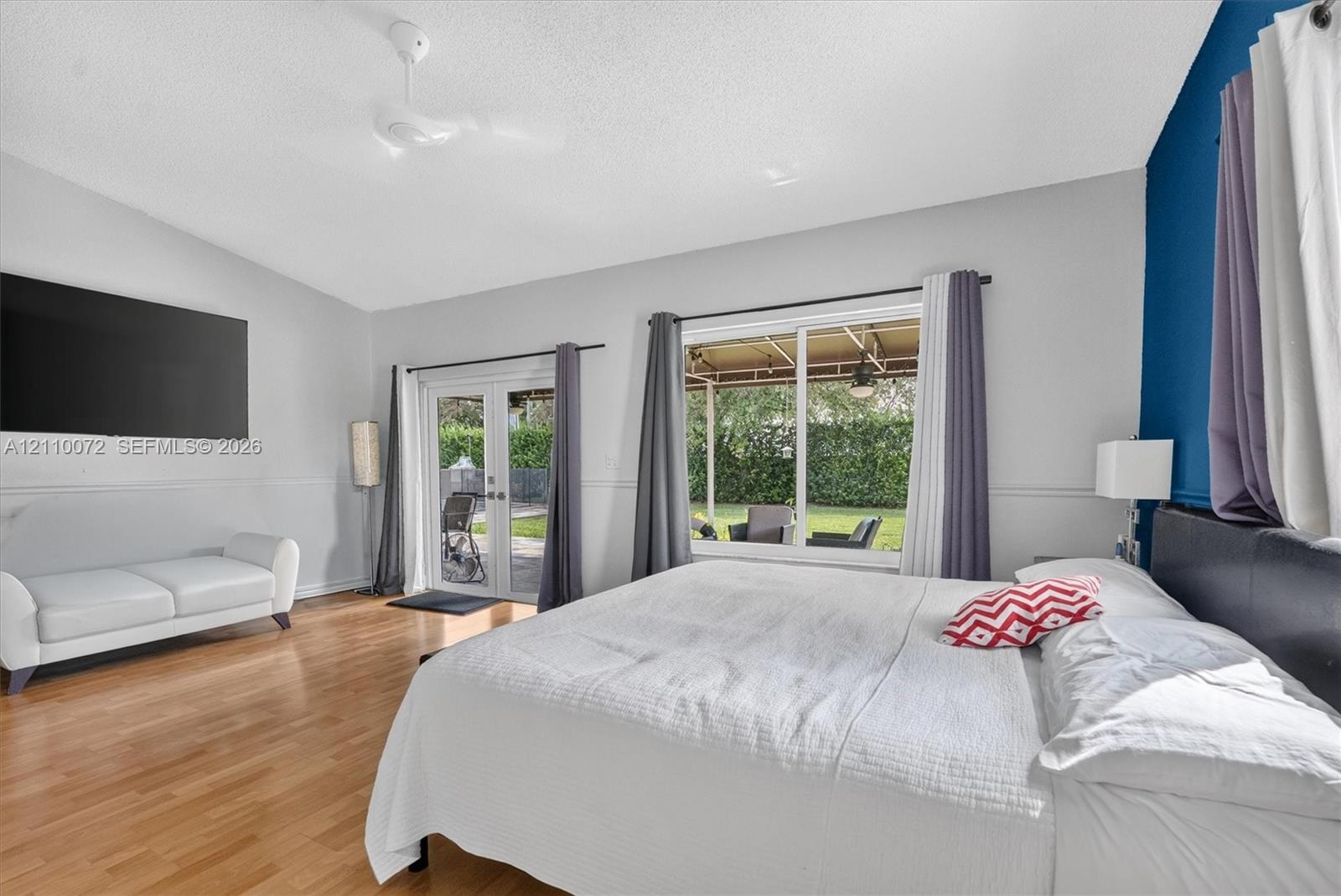 Spacious bedroom featuring vaulted ceilings, wood-finish flooring, and glass French doors