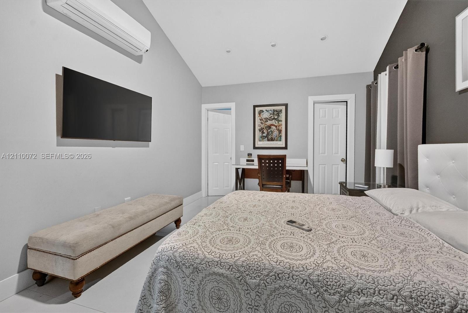 Vaulted ceiling featuring recessed lighting, wall-mounted ductless climate control unit, and crisp white tile flooring