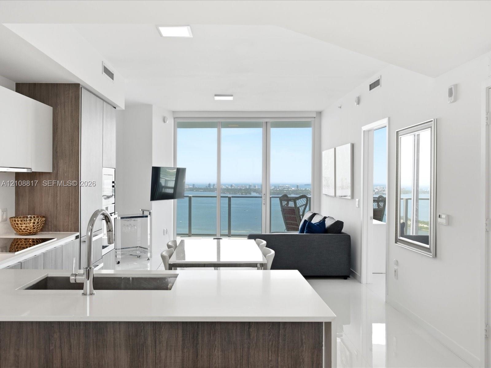 Contemporary kitchen featuring two-tone cabinetry, stone countertops, integrated stainless steel appliances, and polished tile flooring, accented by f