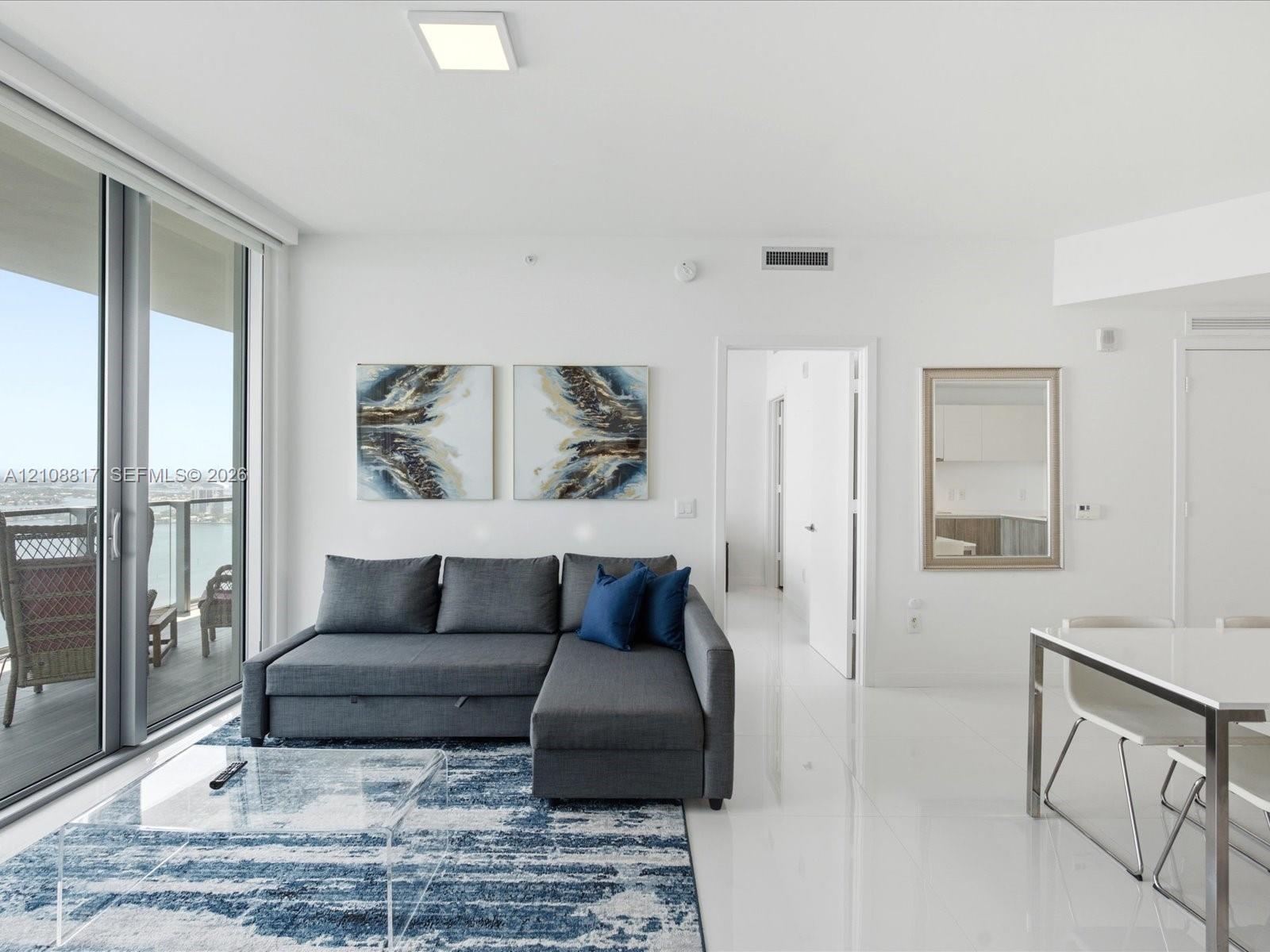 Floor-to-ceiling glass sliding doors, polished tile flooring, recessed square ceiling lighting, and private balcony access
