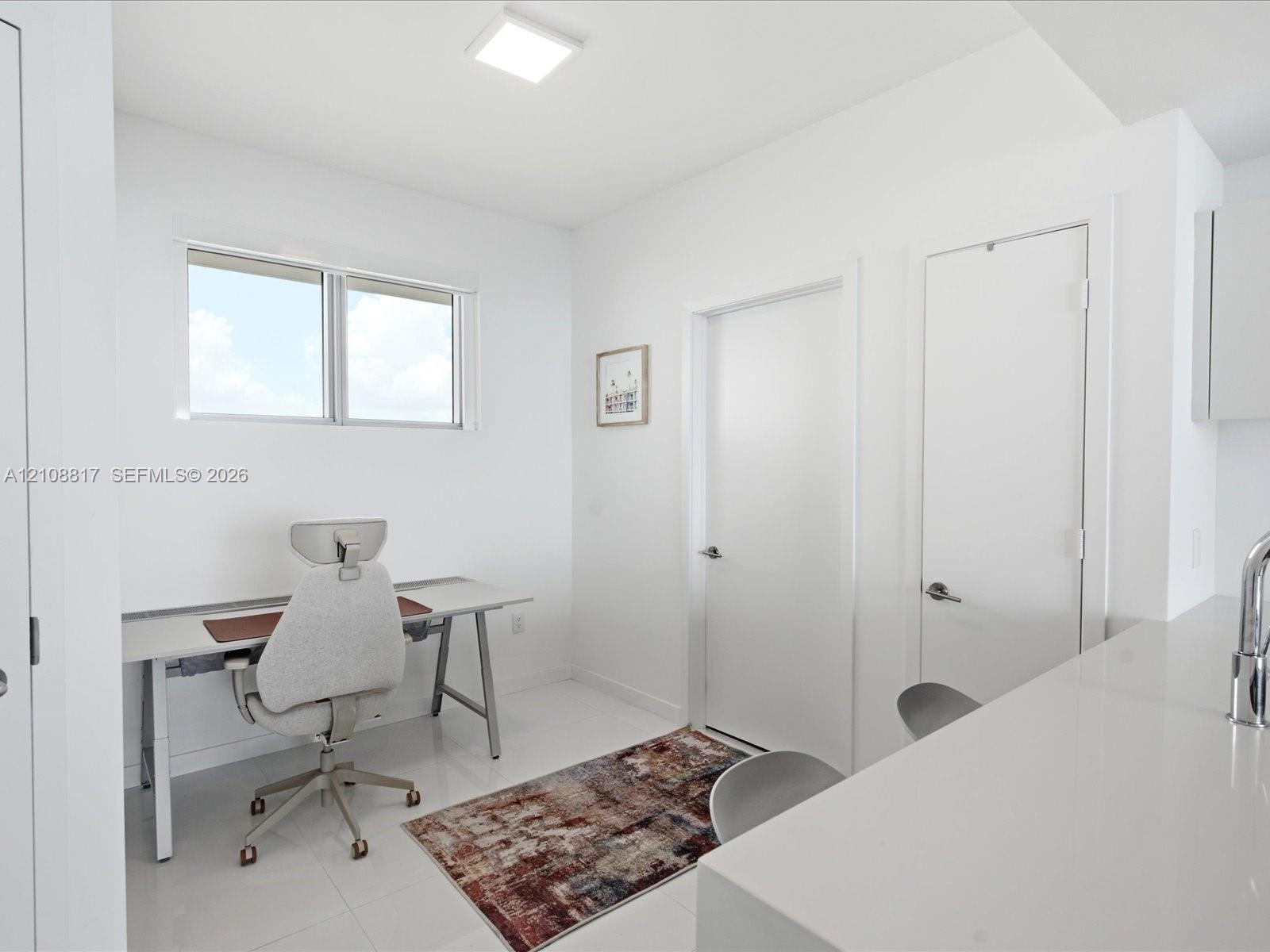 Neutral interior space featuring polished tile flooring, white walls, flush-mount LED ceiling lighting, and a window with a metallic frame