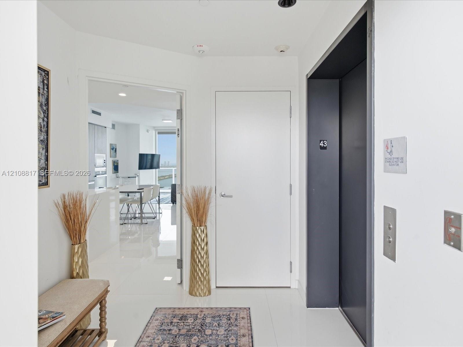 Entry foyer featuring high-gloss tile flooring, a dedicated elevator access point, and recessed ceiling lighting