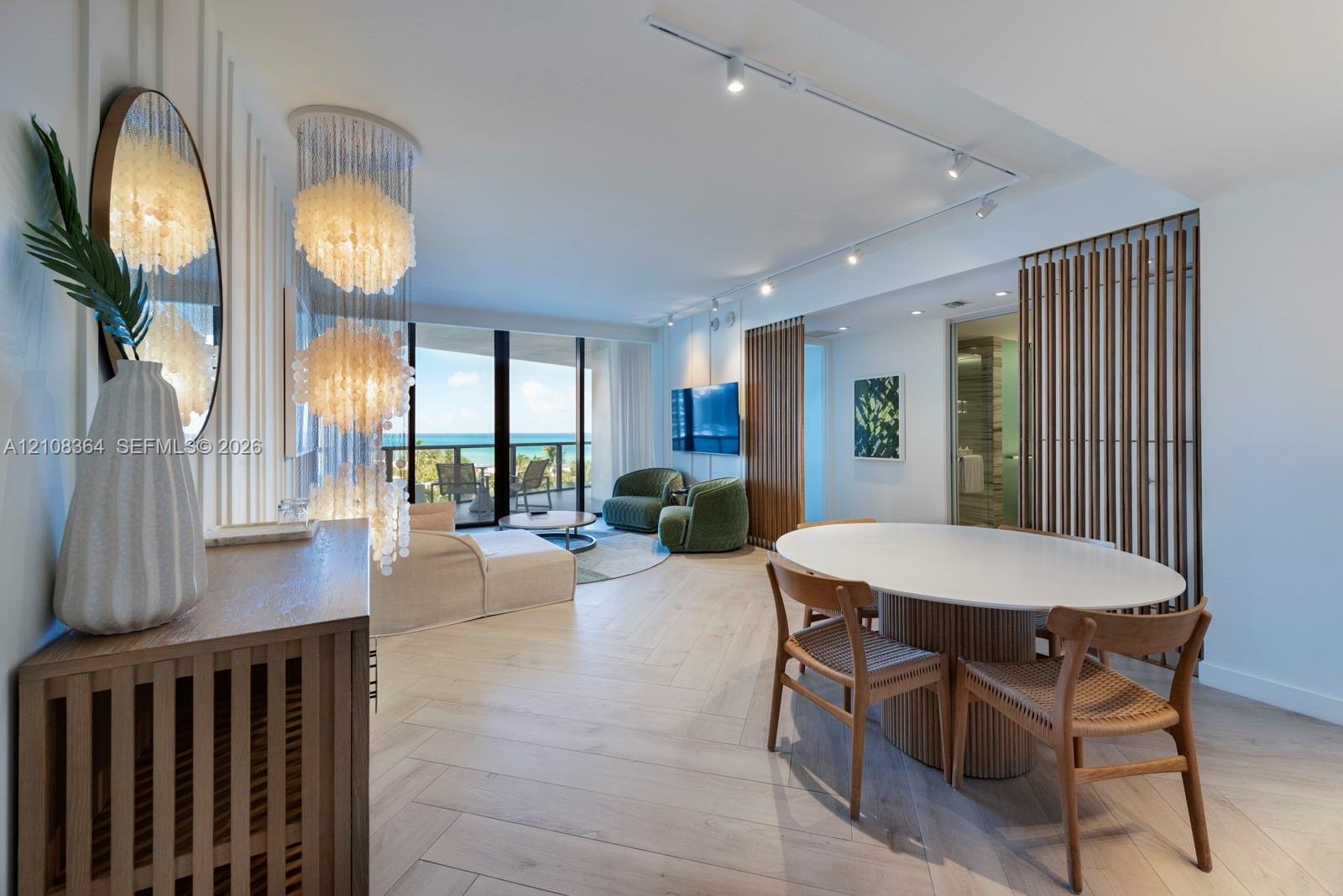 Herringbone wood-finish flooring, floor-to-ceiling glass balcony doors, decorative tiered pendant lighting, vertical wood slat wall detailing, and adj