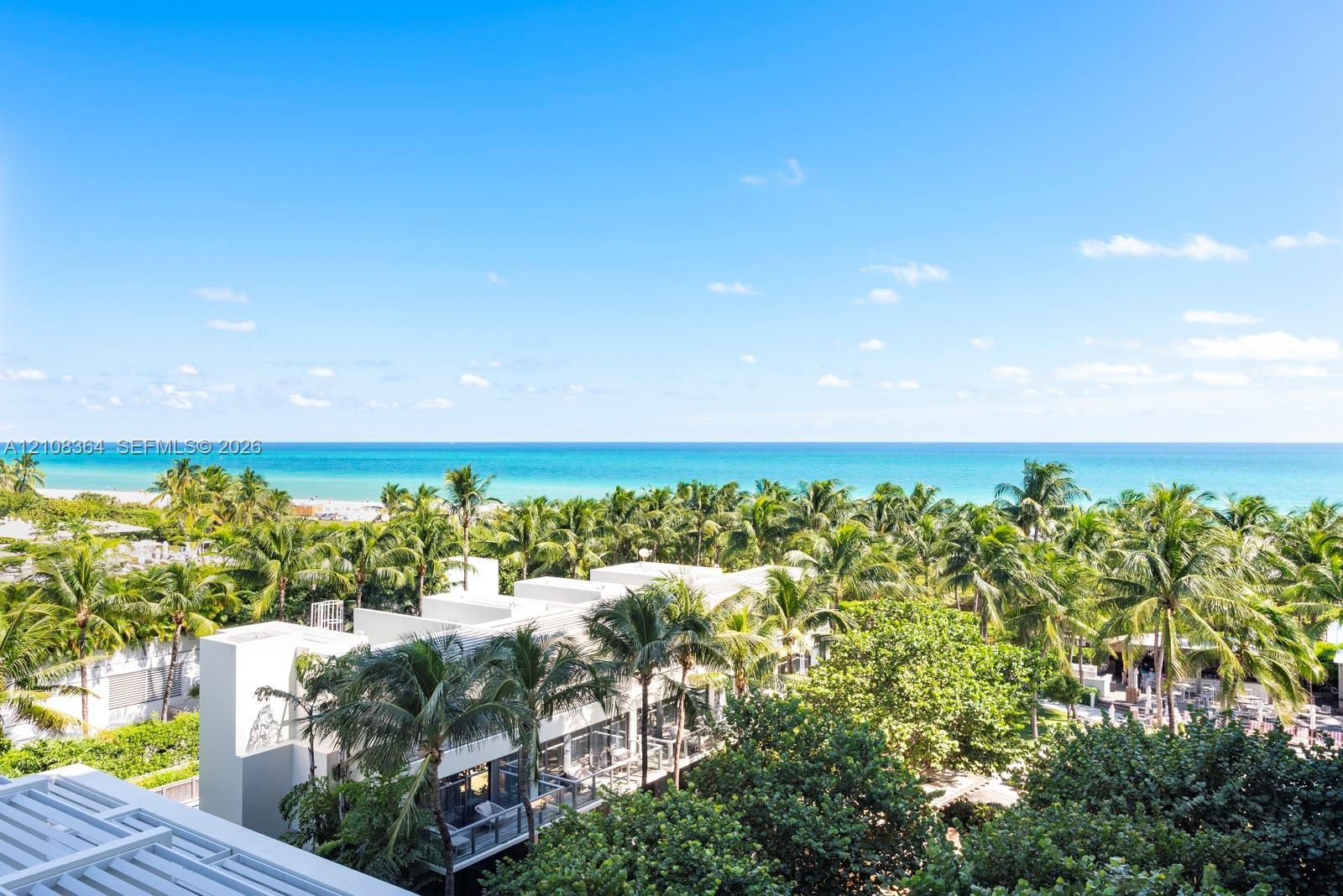 Oceanfront exterior featuring expansive canopy of mature palm trees, multi-level modern architecture, and clear horizon line