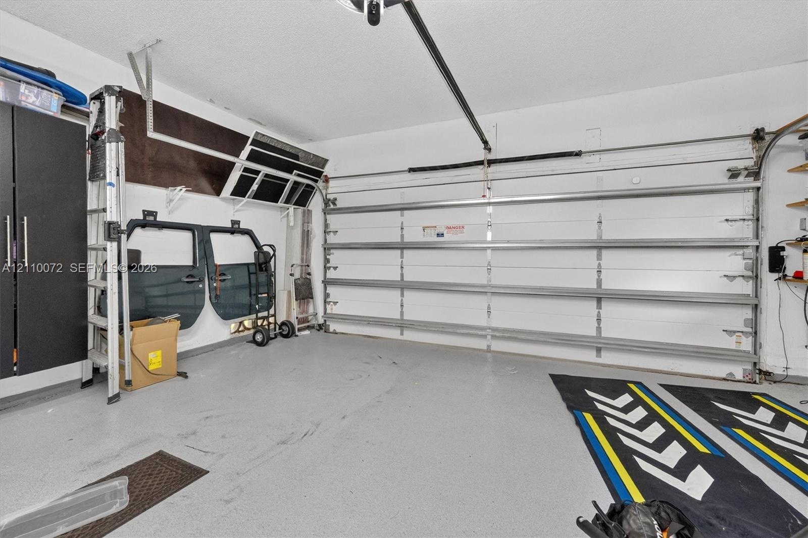 Two-car garage featuring a sectional overhead door, epoxy-coated flooring, and built-in vertical cabinetry
