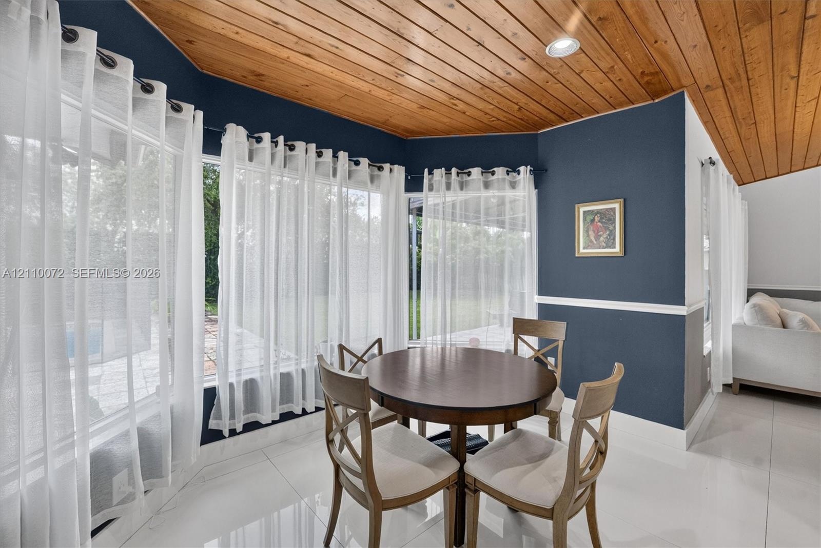 Vaulted wood-plank ceiling, expansive bay of windows, polished tile flooring, and crisp chair rail molding
