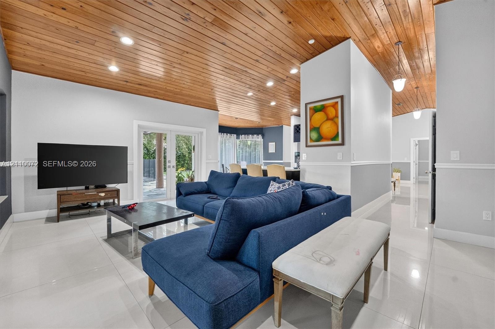 Vaulted wood-plank ceiling, recessed lighting, white tile flooring, and glass-paned double doors