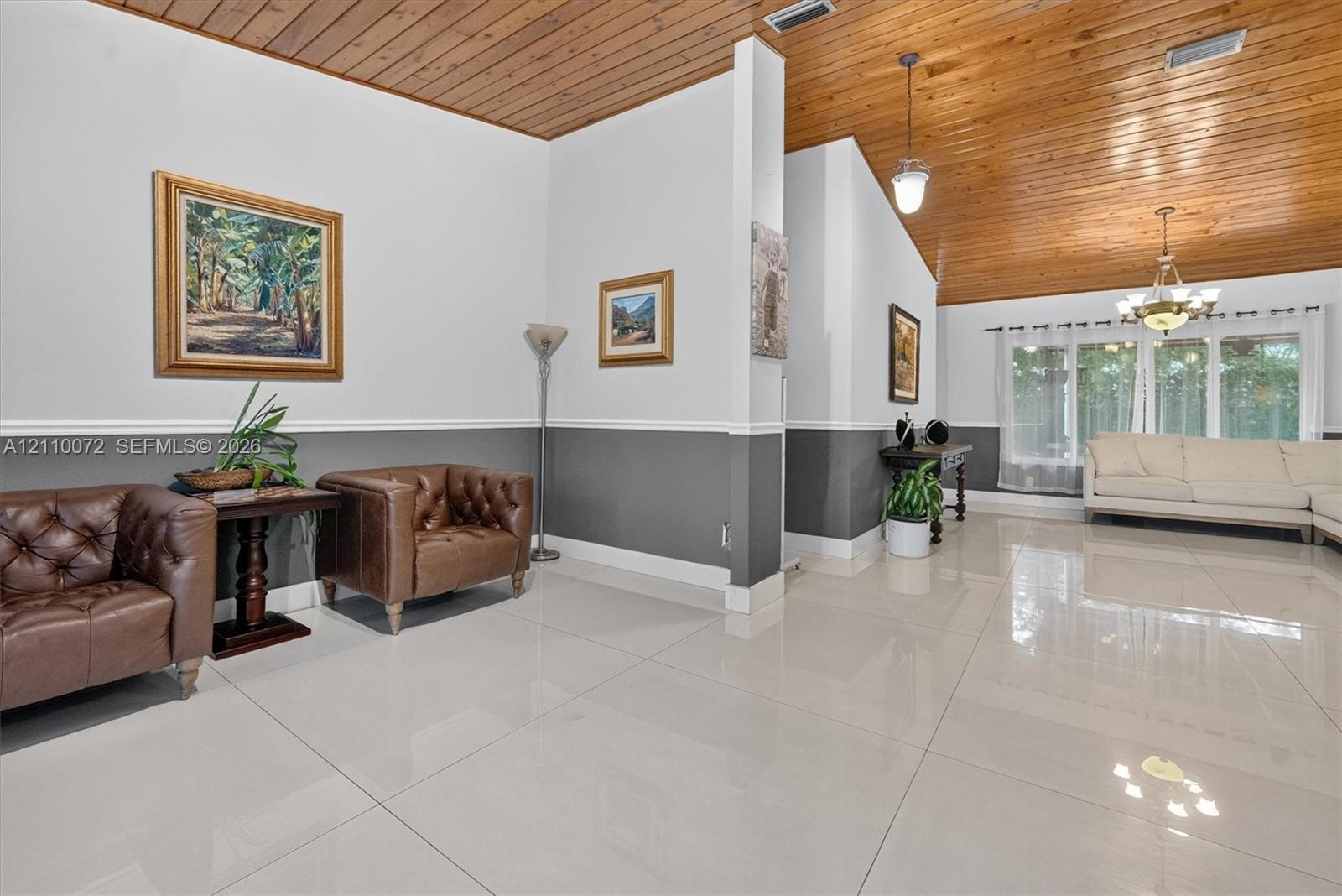 Vaulted wood-plank ceiling, large-format polished tile flooring, two-tone wall treatment with chair rail, and multiple hanging light fixtures