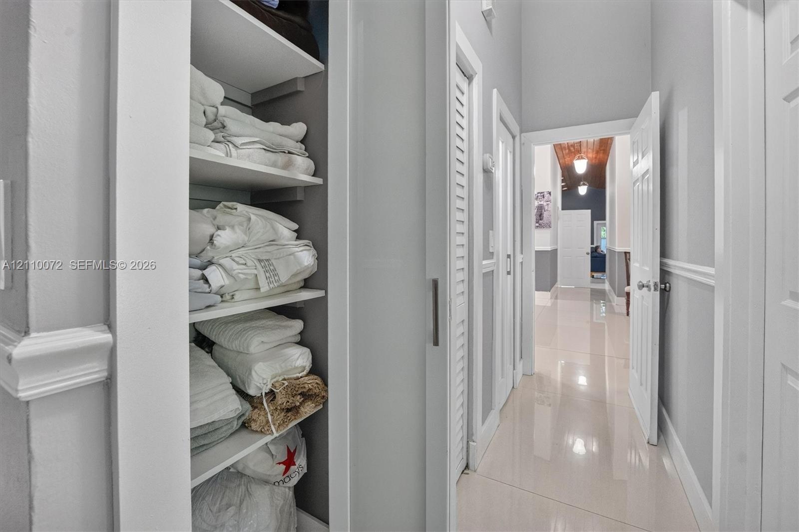 Built-in floor-to-ceiling shelving, crisp white louvered doors, polished tile flooring, and chair rail molding