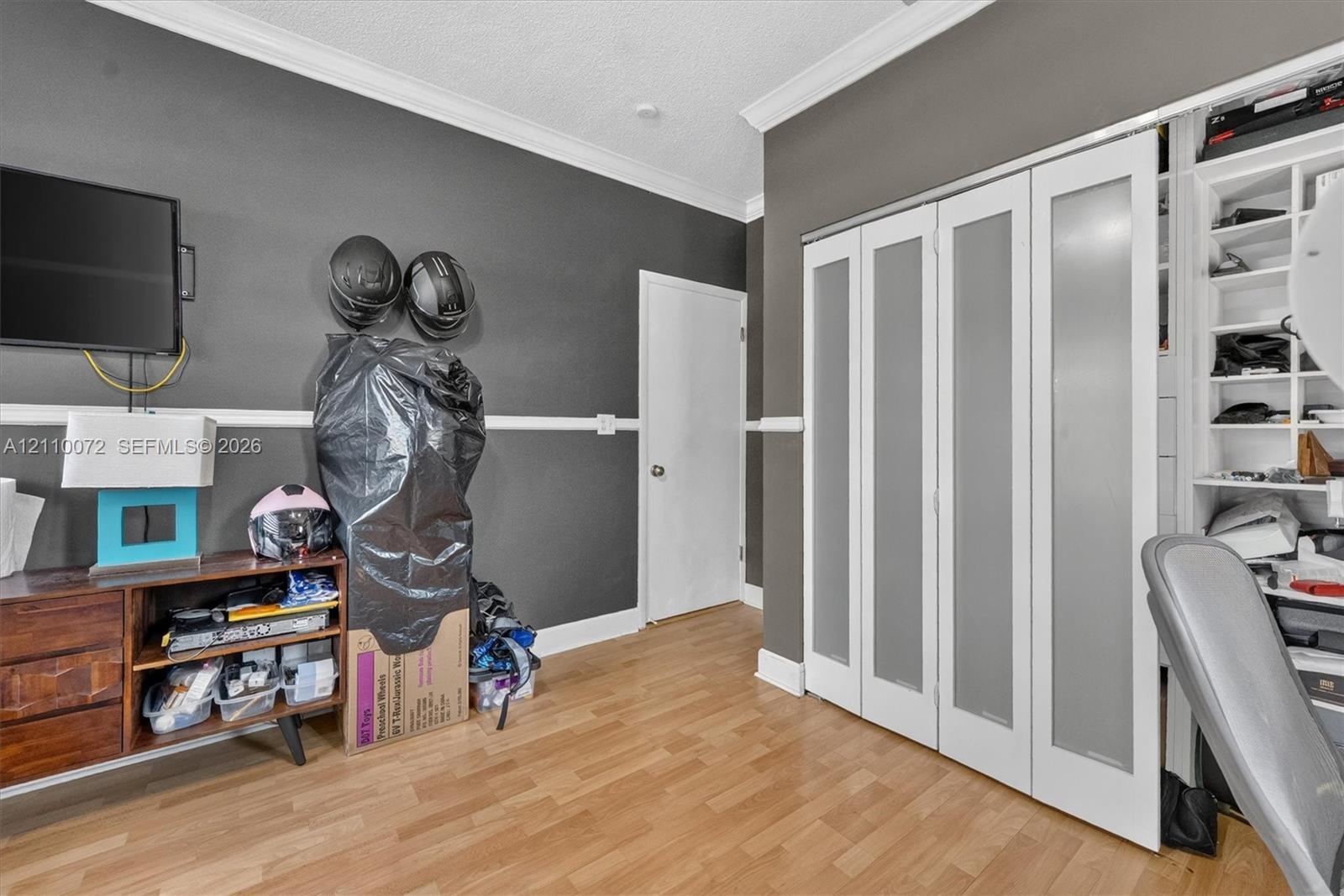 Wood-finish flooring, crown molding, chair rail, bi-fold closet doors with frosted glass panels, and built-in shelving unit