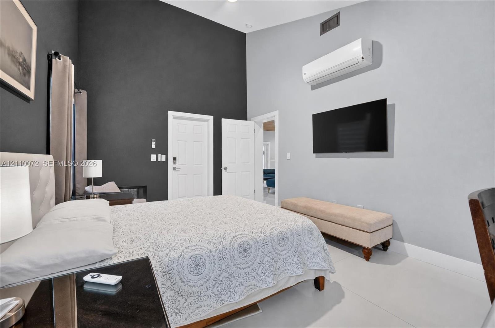 High-ceiling interior featuring a dual-tone accent wall, wall-mounted climate control unit, and crisp light-colored flooring