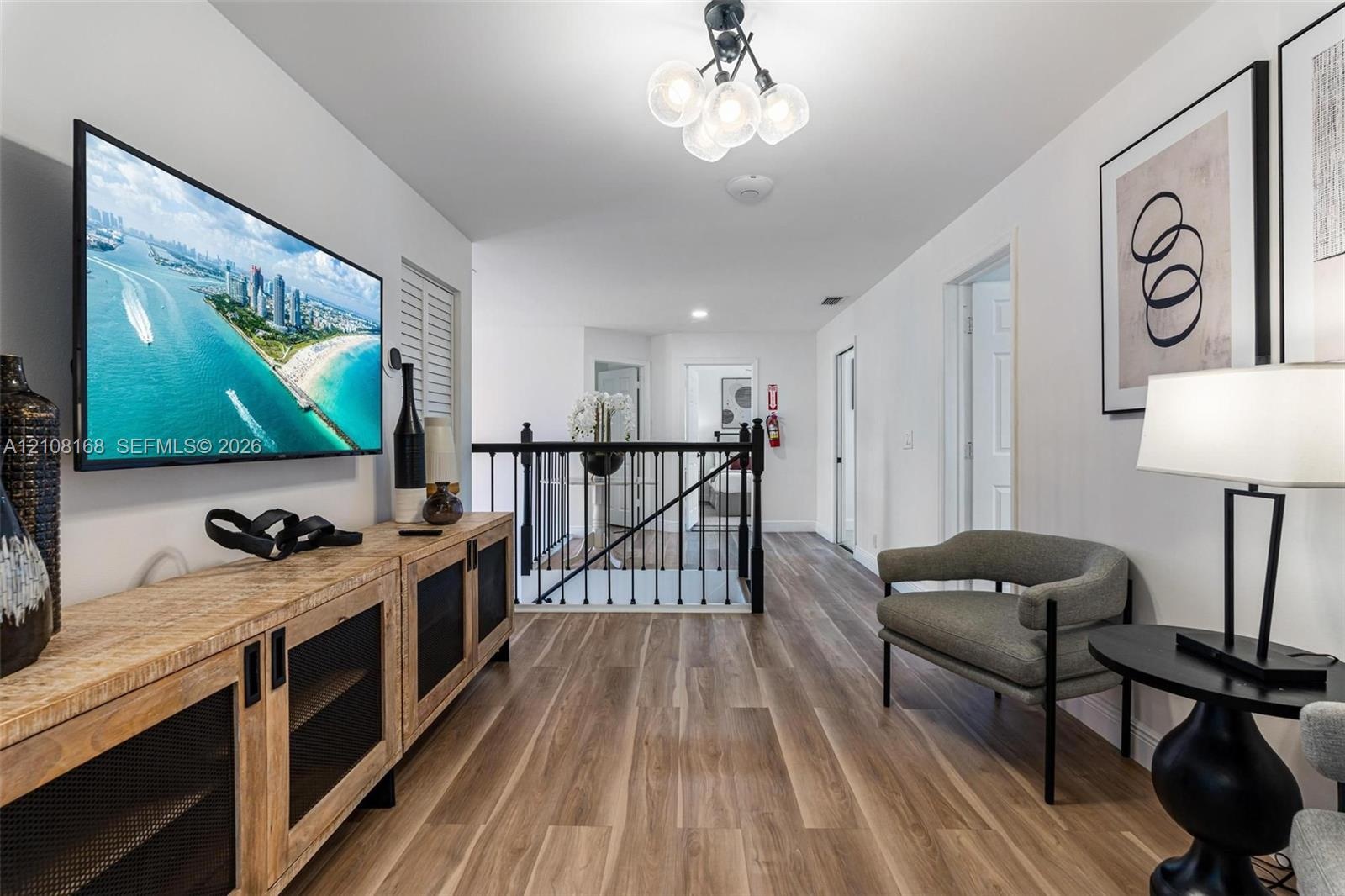 Wood-finish flooring, multi-globe overhead lighting, and metal stair railing with balusters