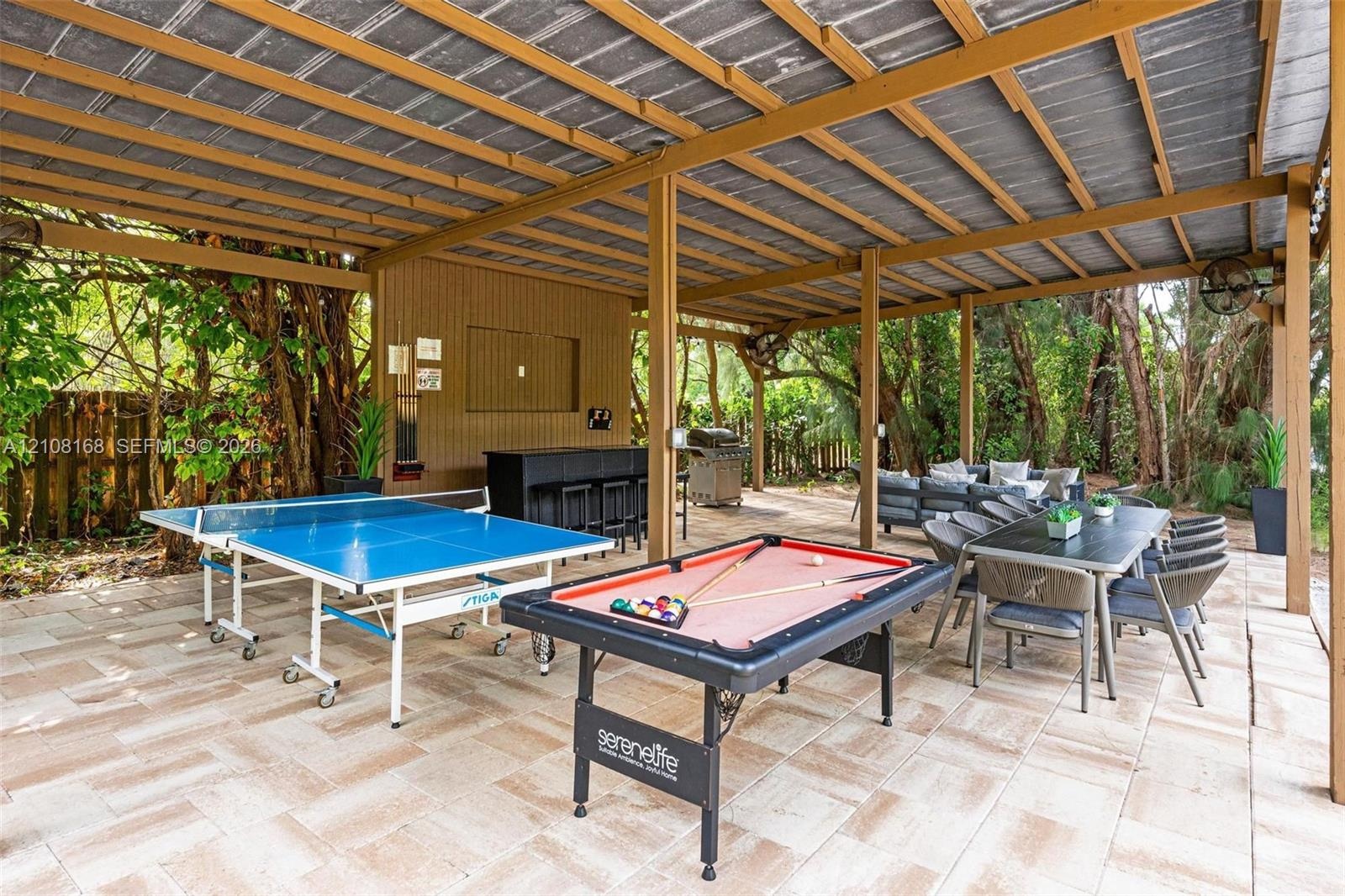 Covered outdoor patio featuring a structural wood frame, stone-tile flooring, built-in bar, and mounted ceiling fans