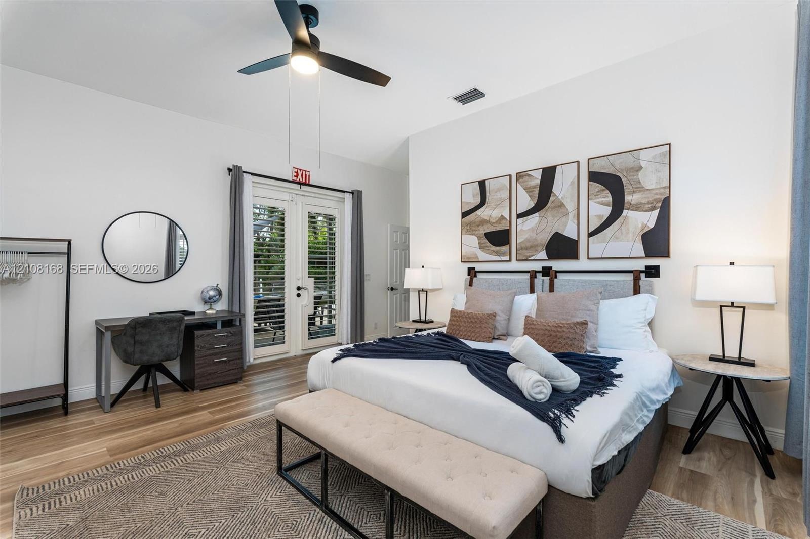 Room featuring wood-finish flooring, vaulted ceilings, a central ceiling fan with integrated lighting, and full-glass French doors with plantation shu