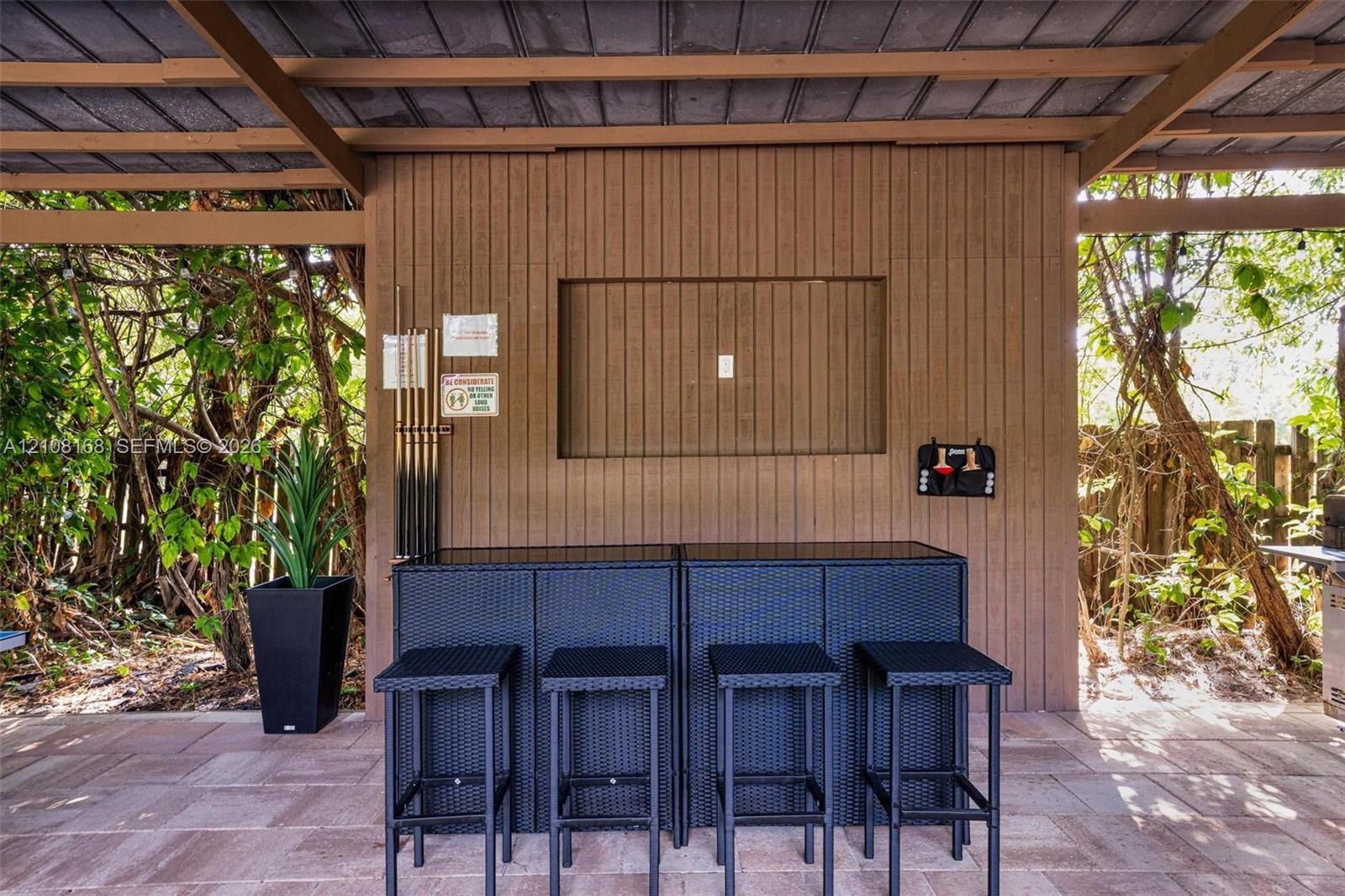 Covered outdoor patio featuring vertical wood-plank siding, stone-paver flooring, and a recessed wall niche