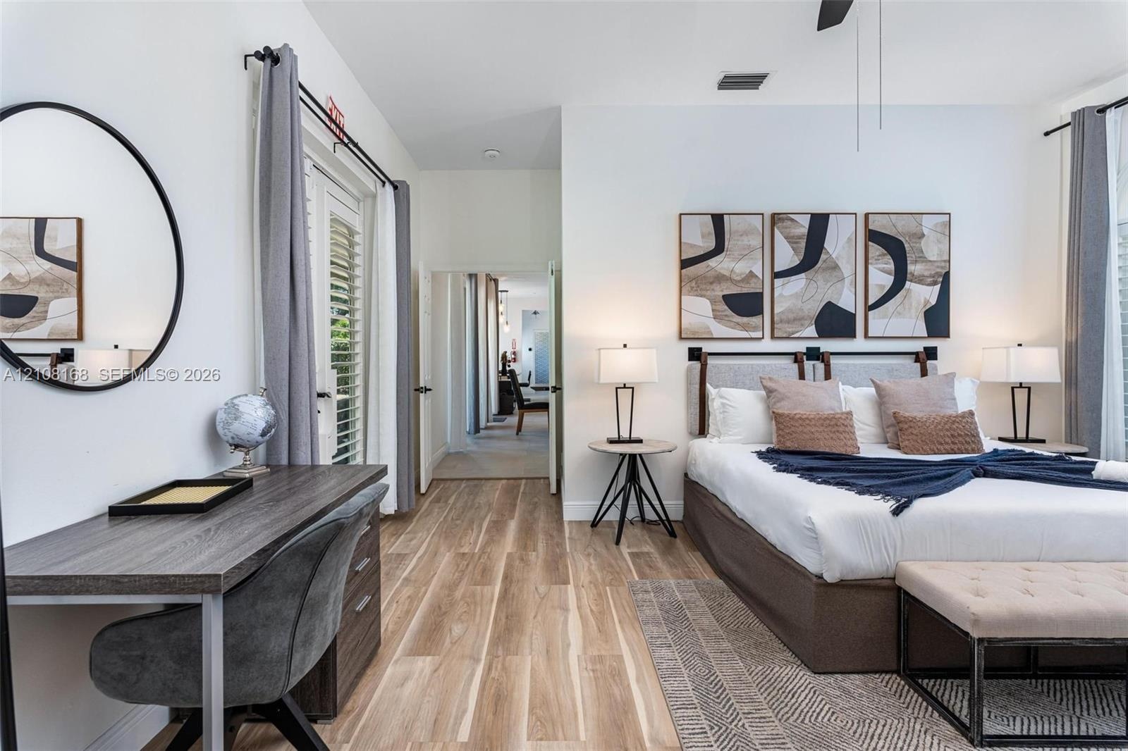 Bedroom featuring wood-finish flooring, high ceilings, ceiling fan, and double glass-paneled doors with shutter-style treatments