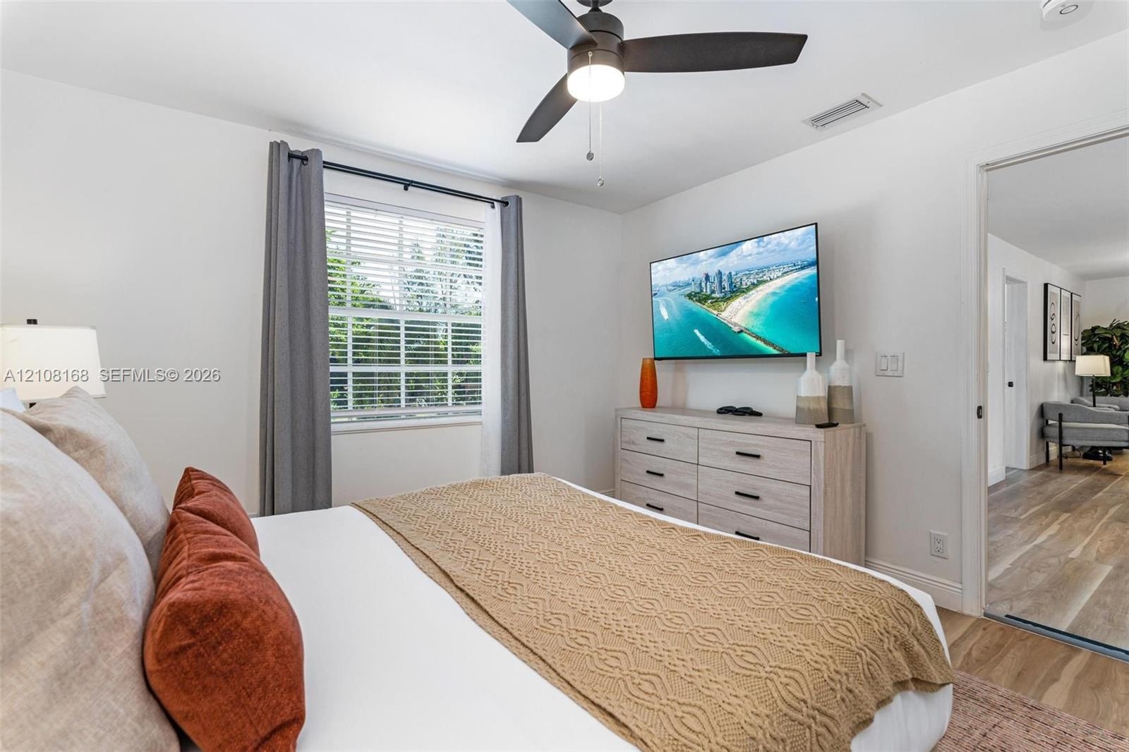 Bedroom featuring a ceiling fan with integrated light, wood-finish flooring, and a single-hung window with horizontal blinds