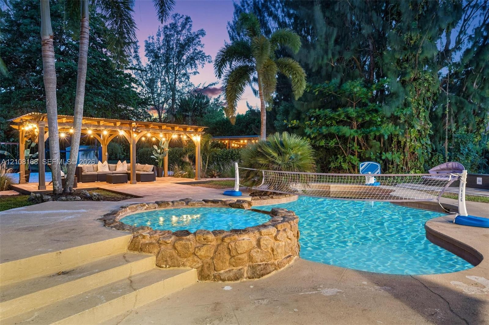 Outdoor space featuring a swimming pool, an integrated spa with stone masonry, a wood-frame pergola, and concrete decking