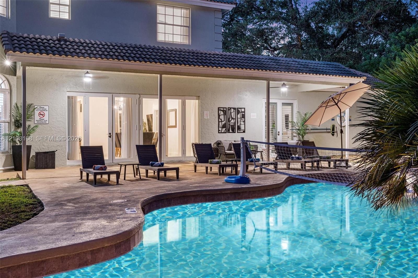 Covered patio featuring a tiled roof and recessed lighting, concrete pool deck, and free-form swimming pool with multi-panel glass exterior doors
