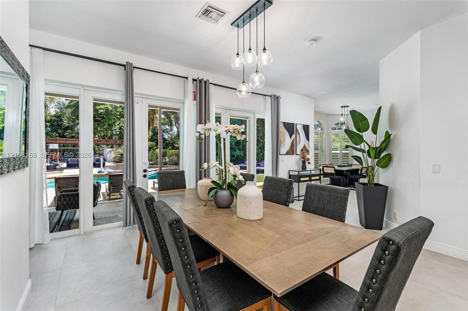 Dining area featuring large-format light tile flooring, multi-light glass pendant fixture, and glass-paneled double doors providing outdoor access