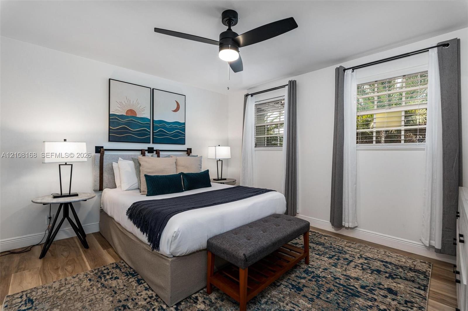 Wood-finish flooring, dual windows with multi-pane glass, and a modern matte black ceiling fan with integrated lighting
