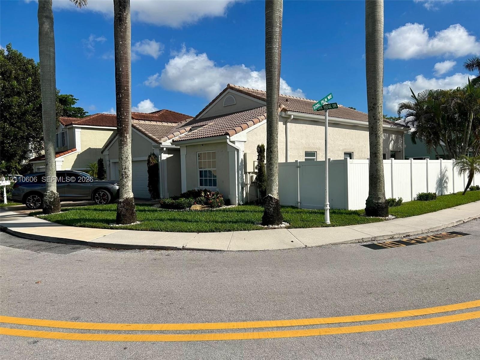 Single-story residence featuring a tile roof, stucco exterior, corner lot positioning, and white privacy fencing
