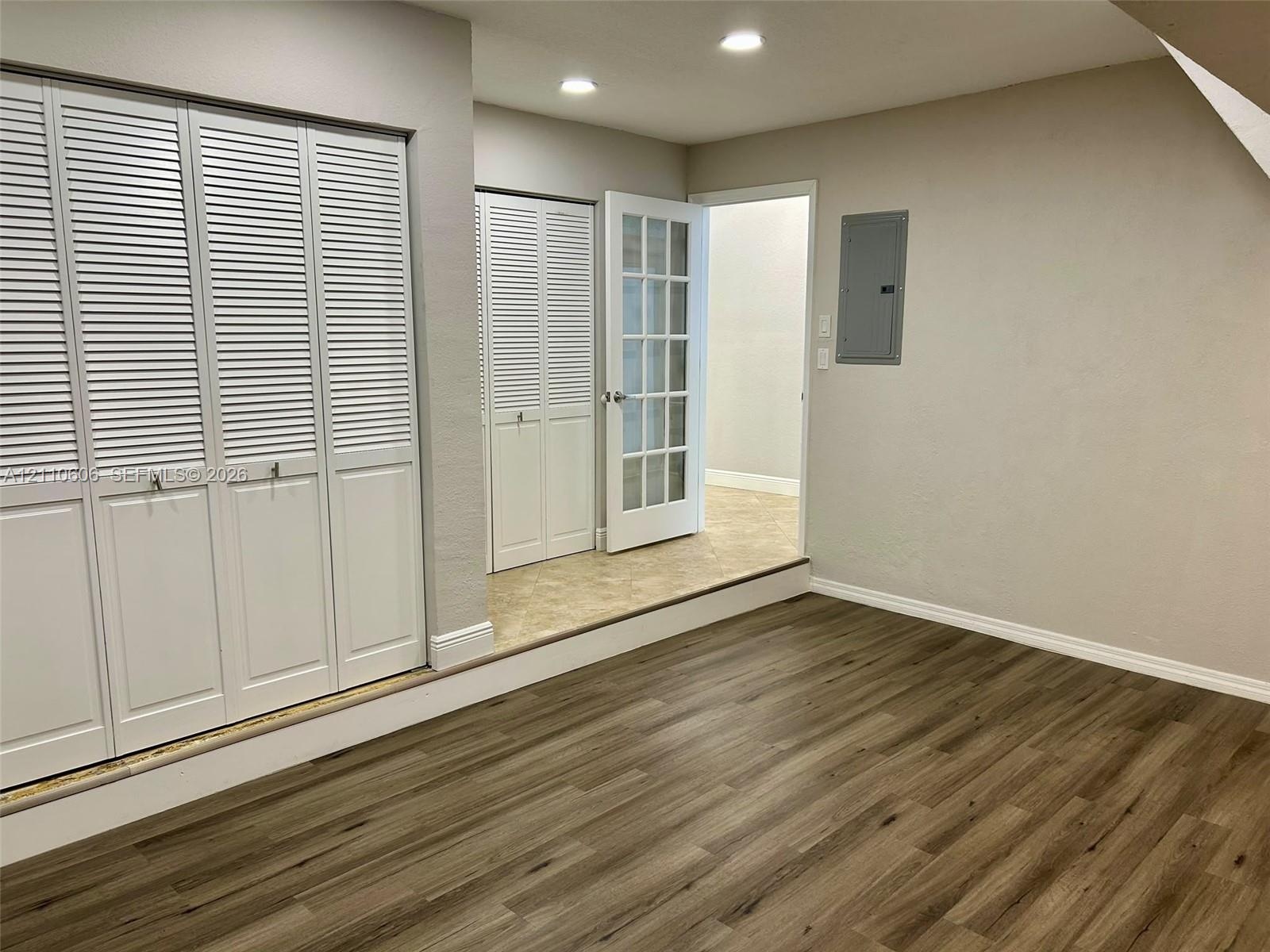 Wood-finish flooring, white louvered closet doors, recessed lighting, and a multi-pane glass door