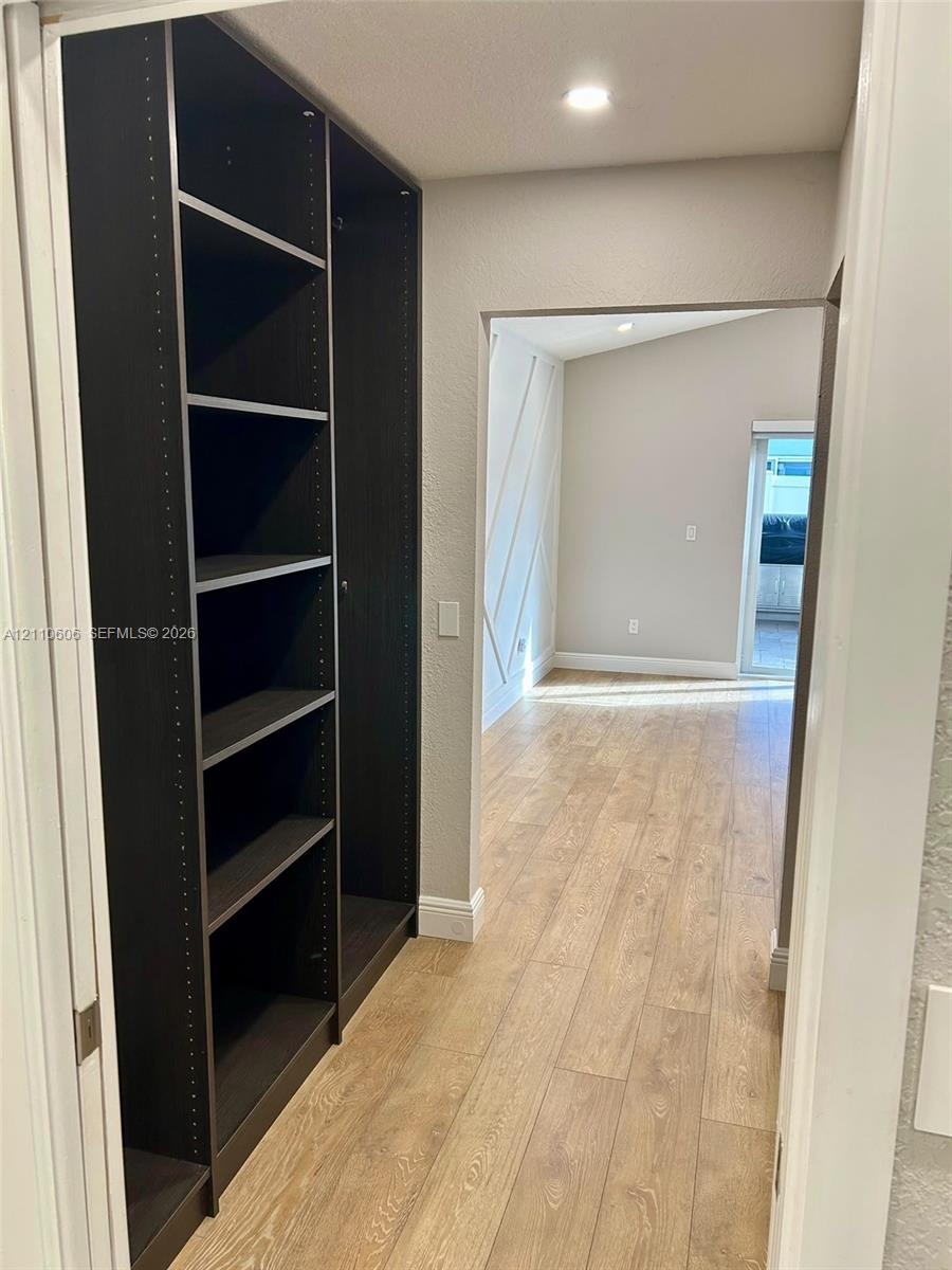 Built-in dark wood-finish cabinetry, light-toned wood-finish flooring, and walls featuring decorative geometric millwork