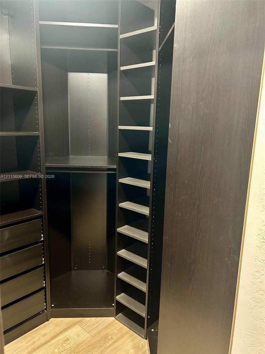 Custom built-in closet organization system featuring dark wood-finish cabinetry, floor-to-ceiling adjustable shelving, multi-tiered hanging rods, and 