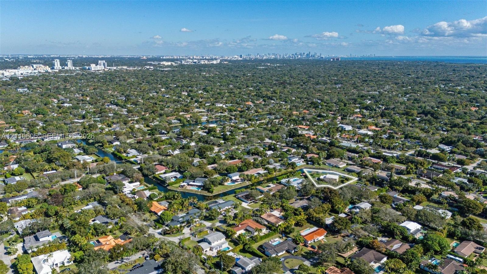 Aerial perspective of a residential property featuring a large lot, perimeter landscaping, and proximity to a canal