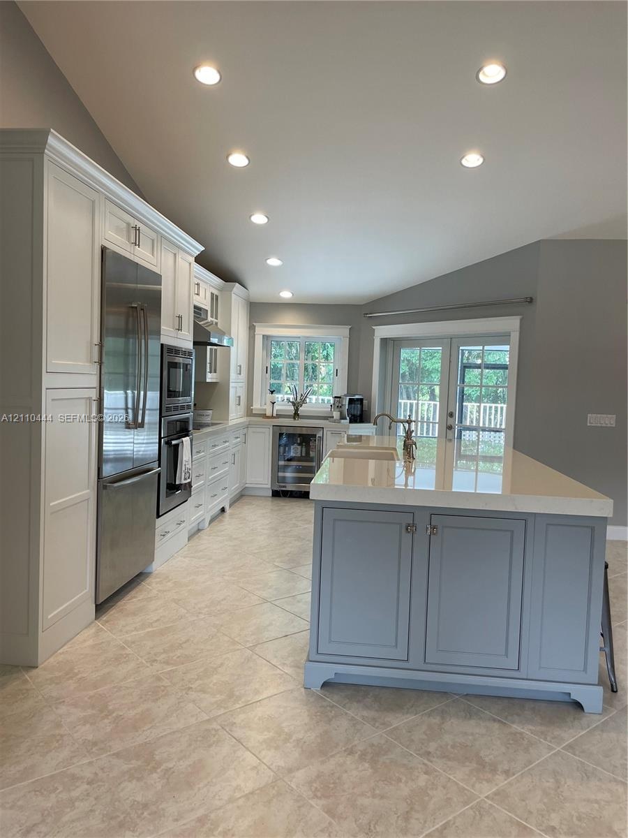Kitchen featuring white cabinetry, center island with stone countertop, stainless steel appliances, recessed lighting, and tile flooring