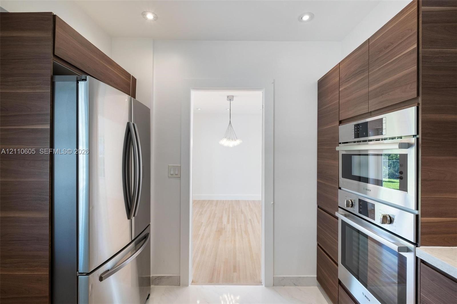 Kitchen featuring full-height wood-finish cabinetry, stainless steel French-door refrigerator, built-in stainless steel double wall ovens, and recesse