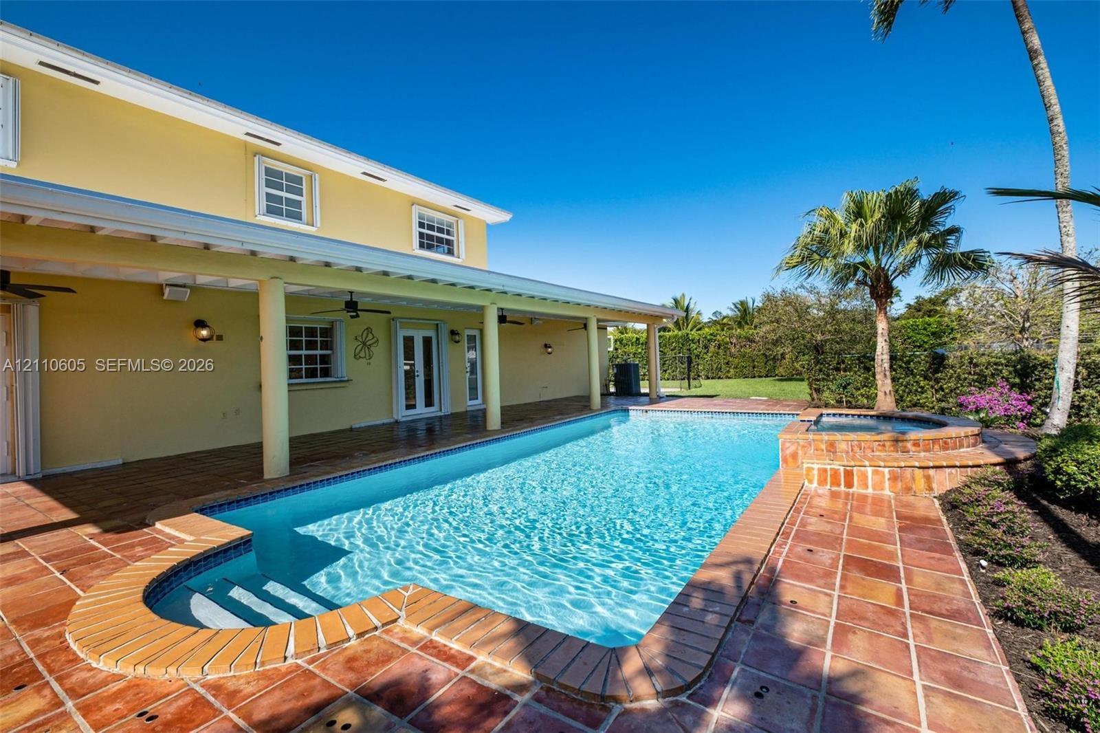 Covered patio with recessed ceiling fans, swimming pool, raised spillover spa, and terracotta-style tile decking