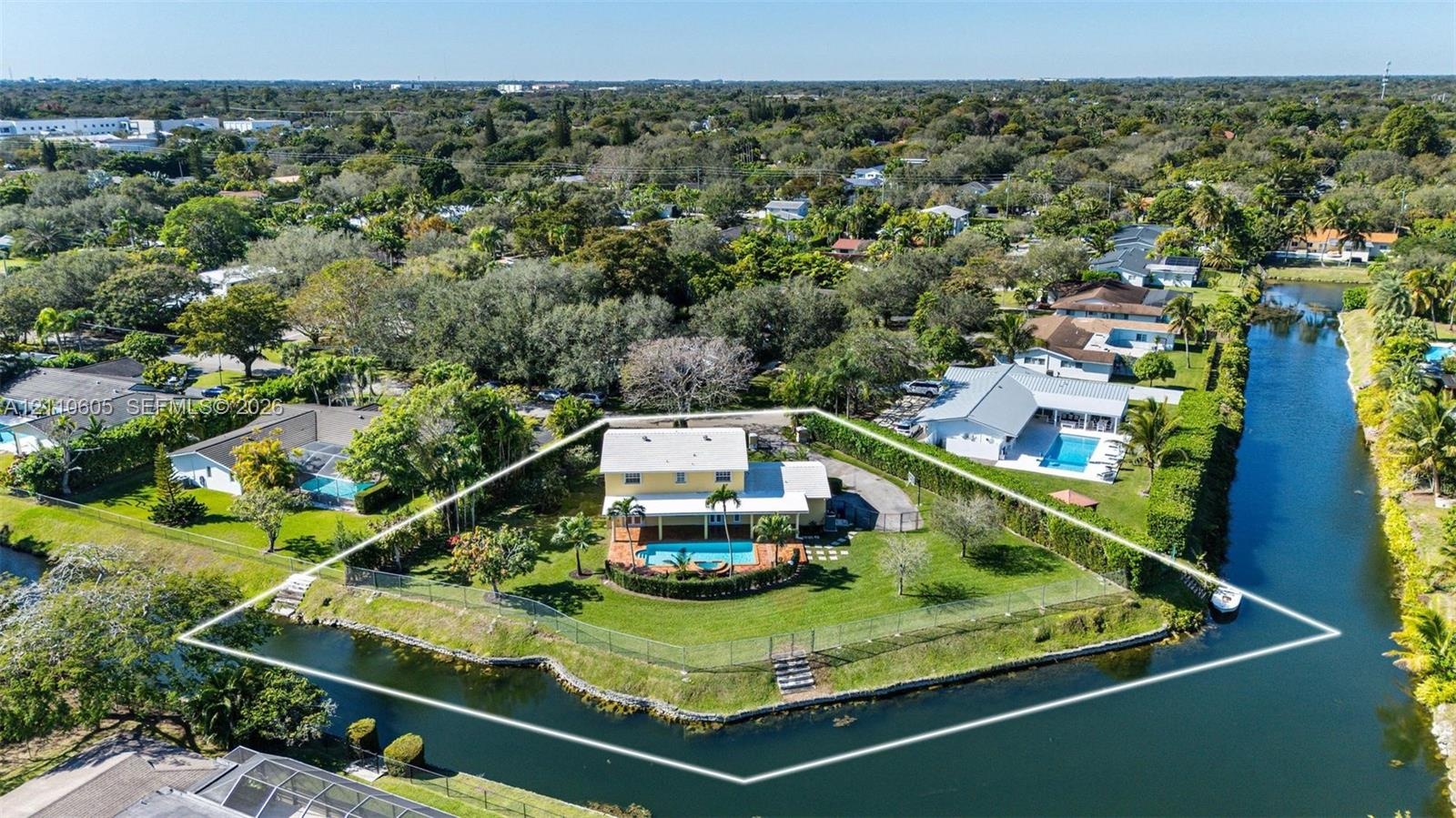 Waterfront property featuring a two-story residence, an expansive rear yard, an in-ground swimming pool, and a perimeter fence