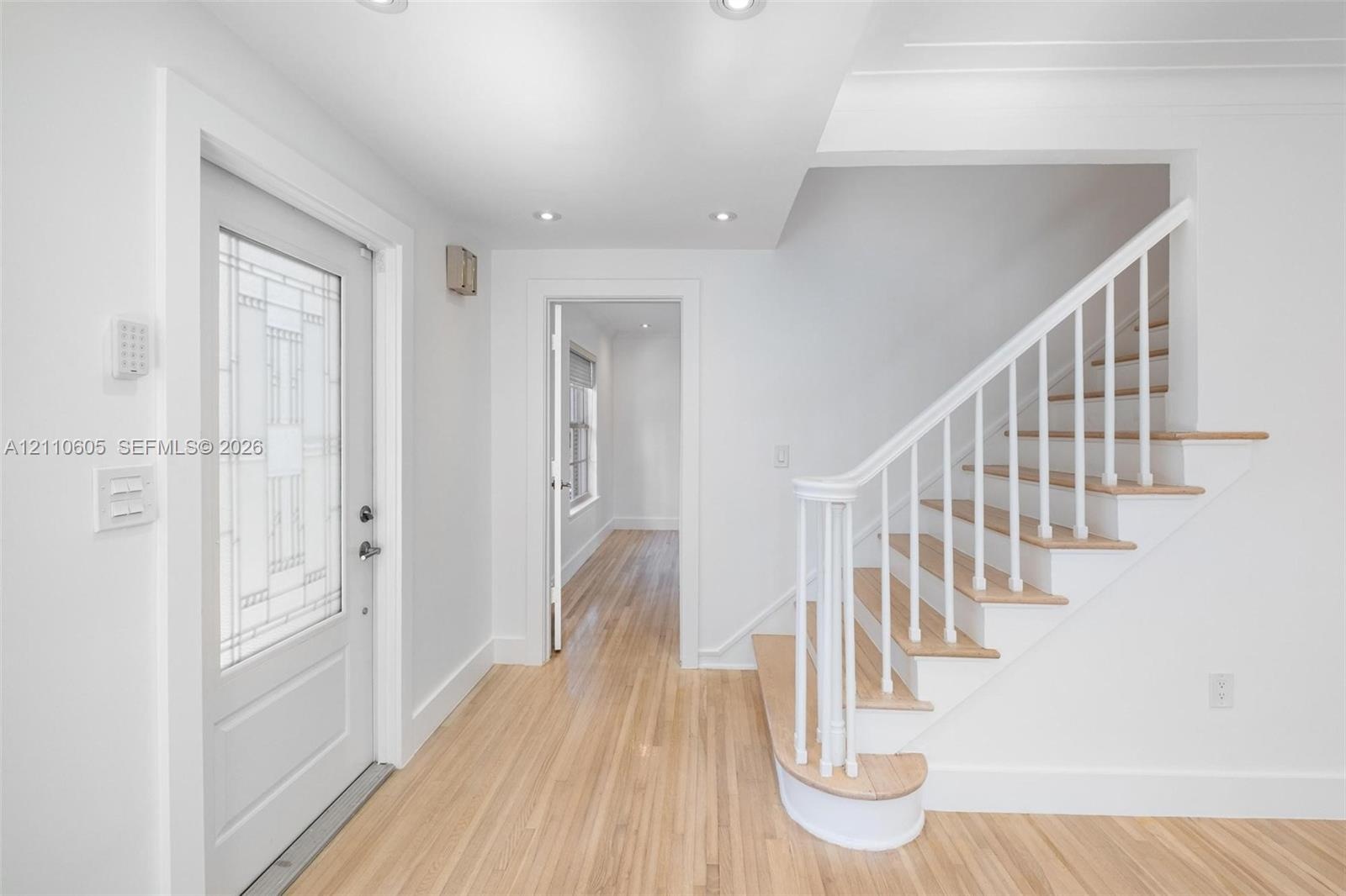 Entryway featuring wood-finish flooring, a decorative glass-panel door, recessed lighting, and a staircase with white spindles and wood-finish treads