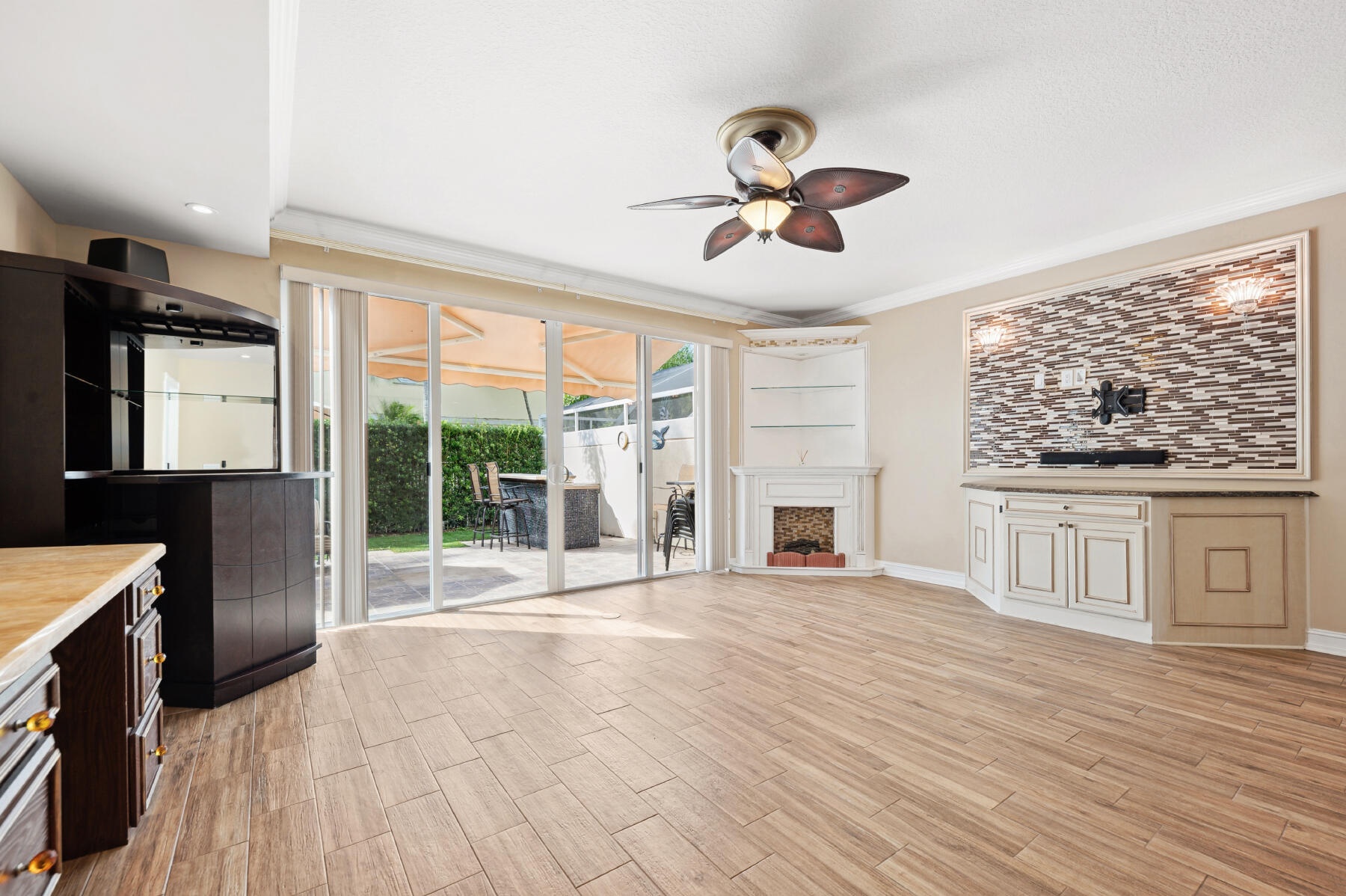 Living space featuring wood-finish flooring, a corner fireplace with built-in shelving, a stone-tiled media wall, multi-panel glass sliding doors, and