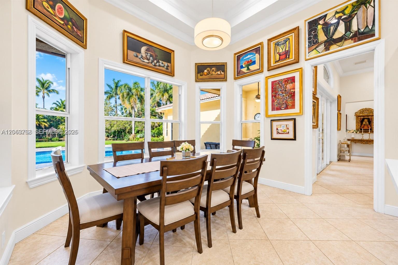 Dining area featuring high tray ceilings, oversized windows, and neutral tile flooring
