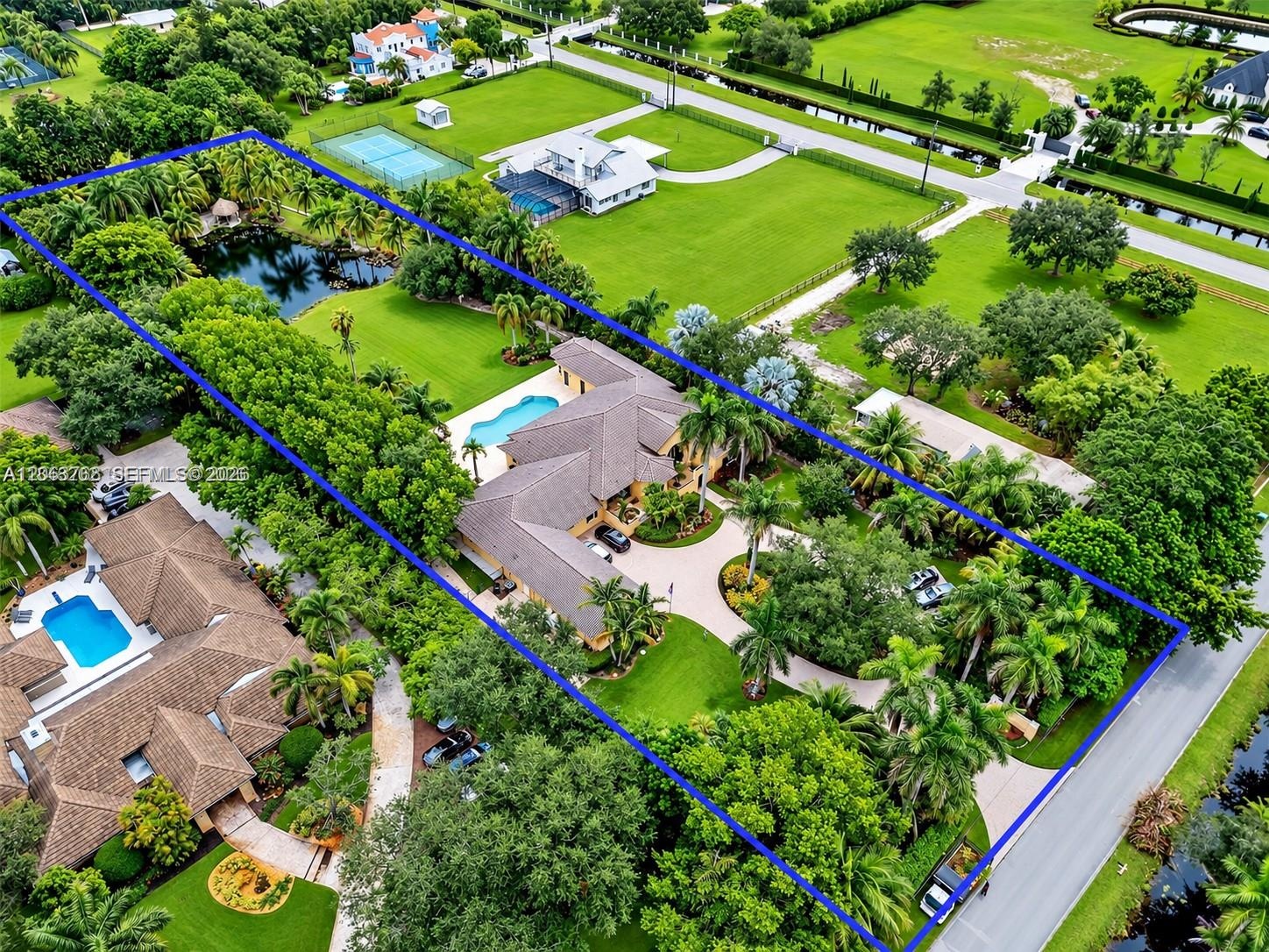 Extensive property grounds featuring a private pond, in-ground swimming pool, mature perimeter landscaping, and a paved circular driveway